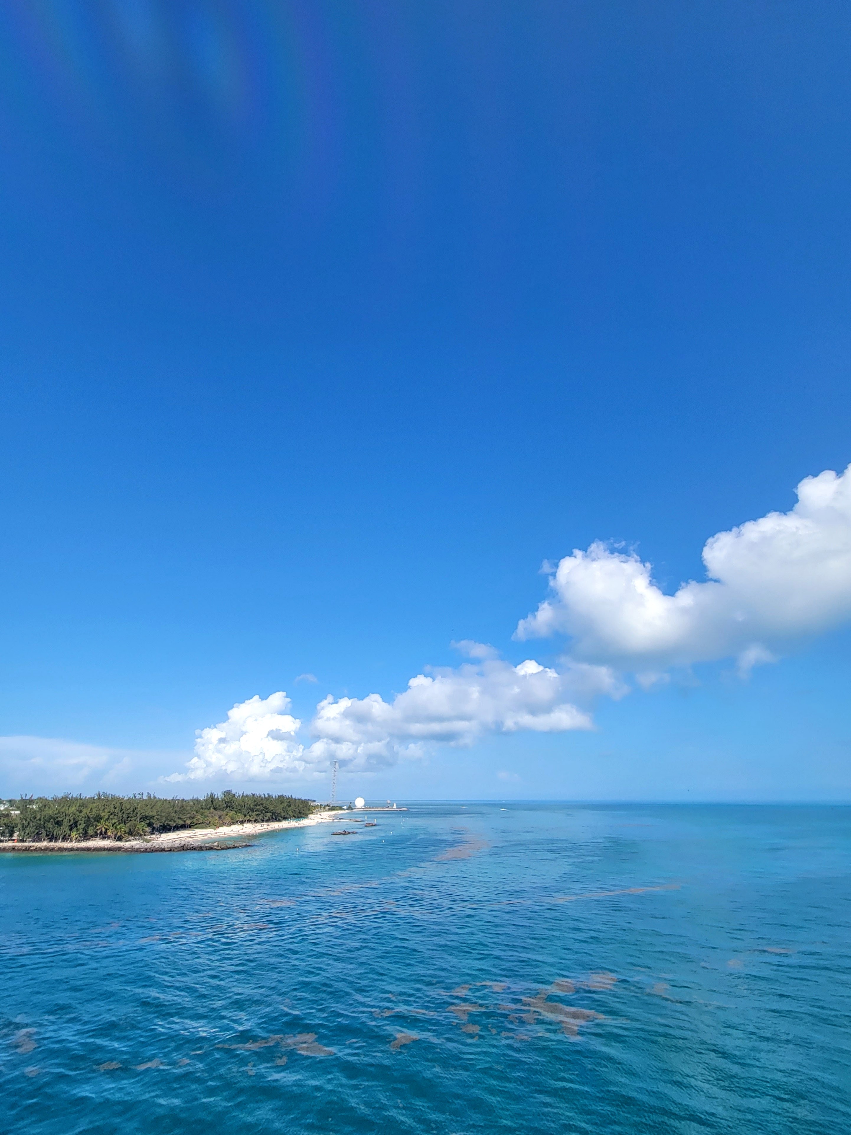 Beautiful view of the ocean with a small stretch of sandy coastline visible in the distance on a sunny day