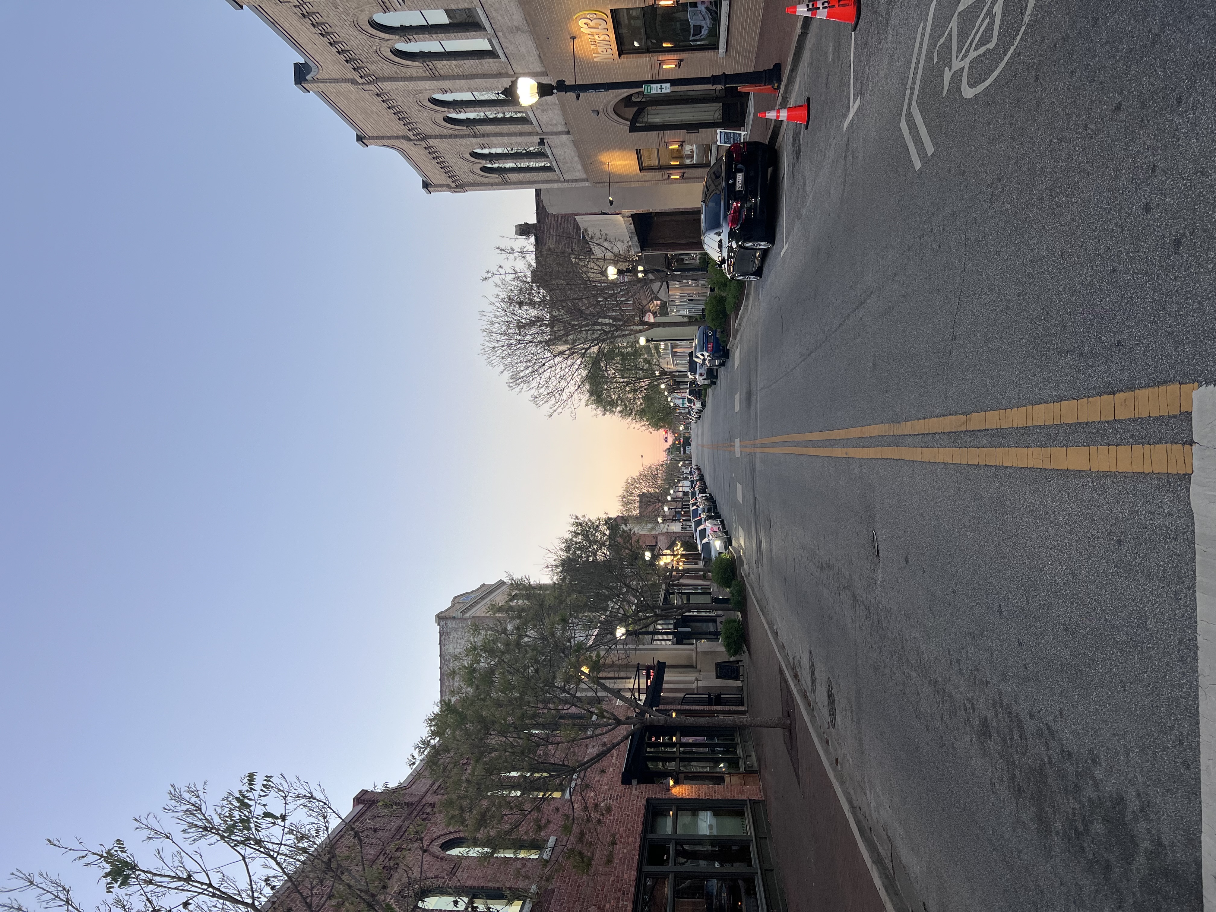 Quaint buildings line the street on a quiet block at dusk.