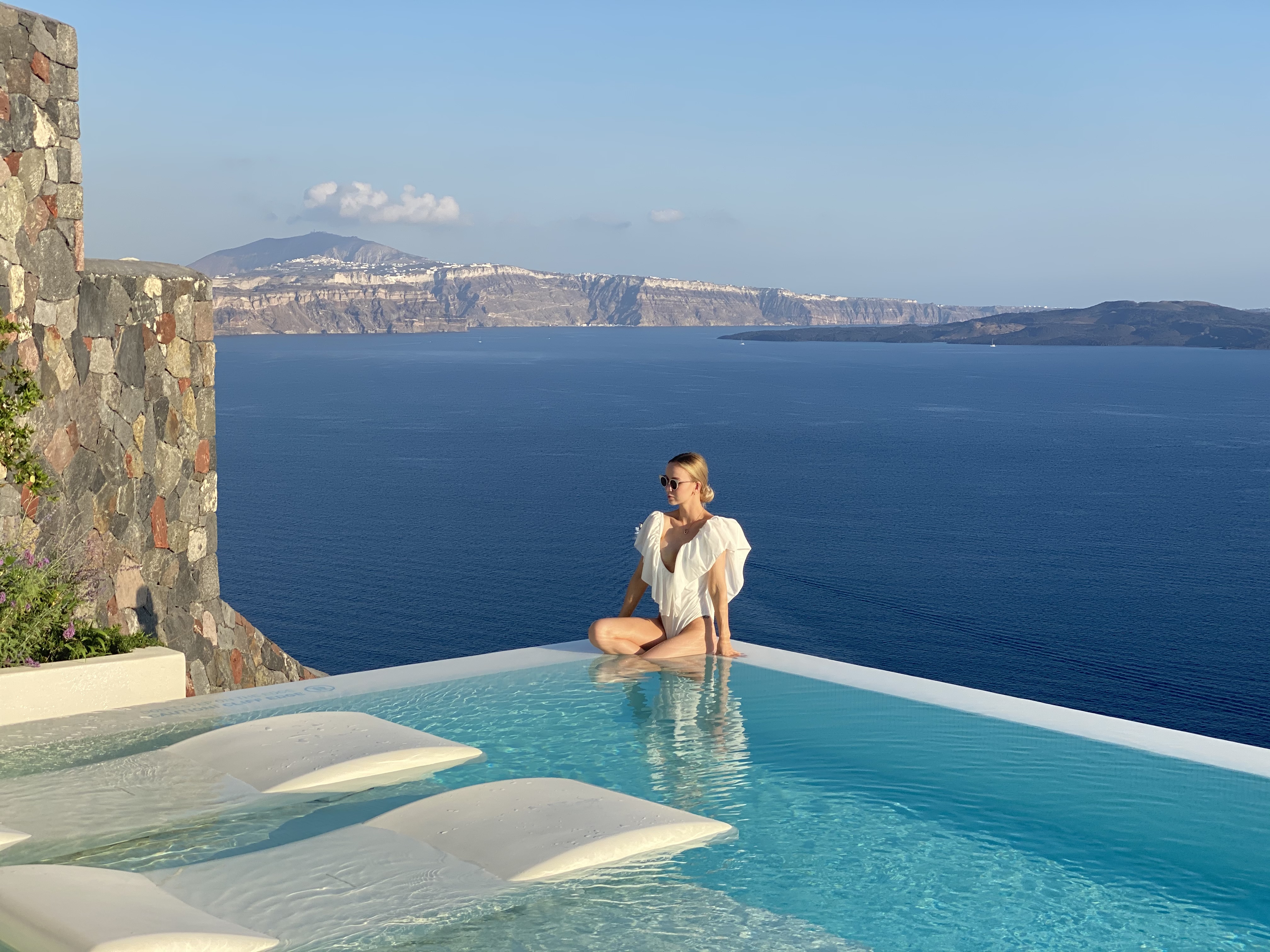 Advisor sitting on the edge of an infinity pool overlooking a stunning seascape
