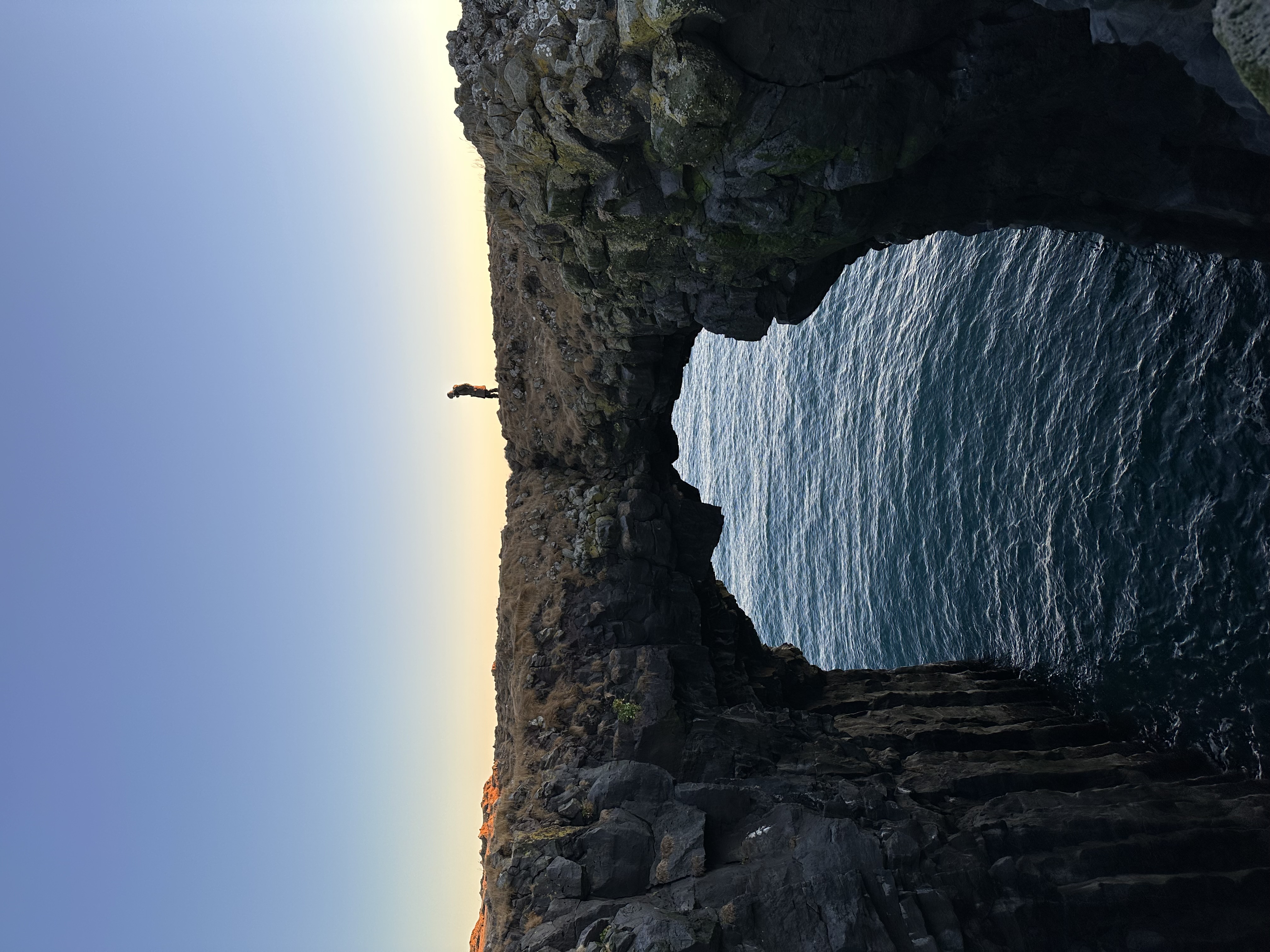 View of a beautiful stone archway over the sea at sunset