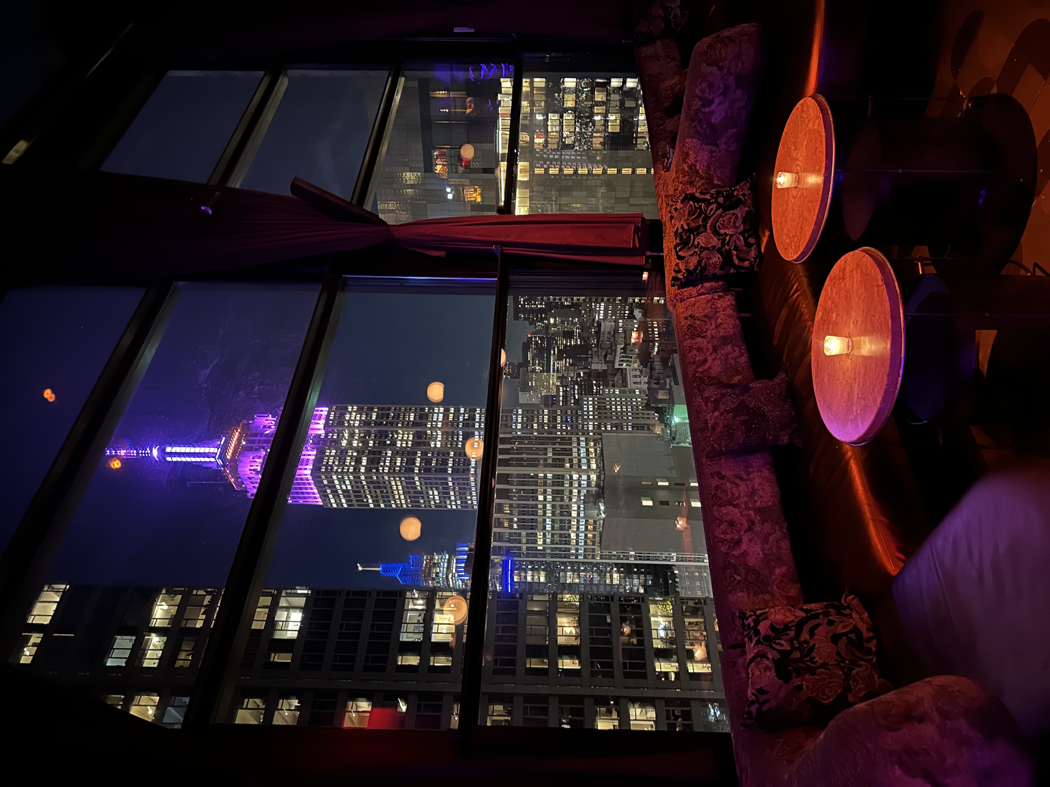View of the Empire State Building lit up in purple light as seen through a window at night