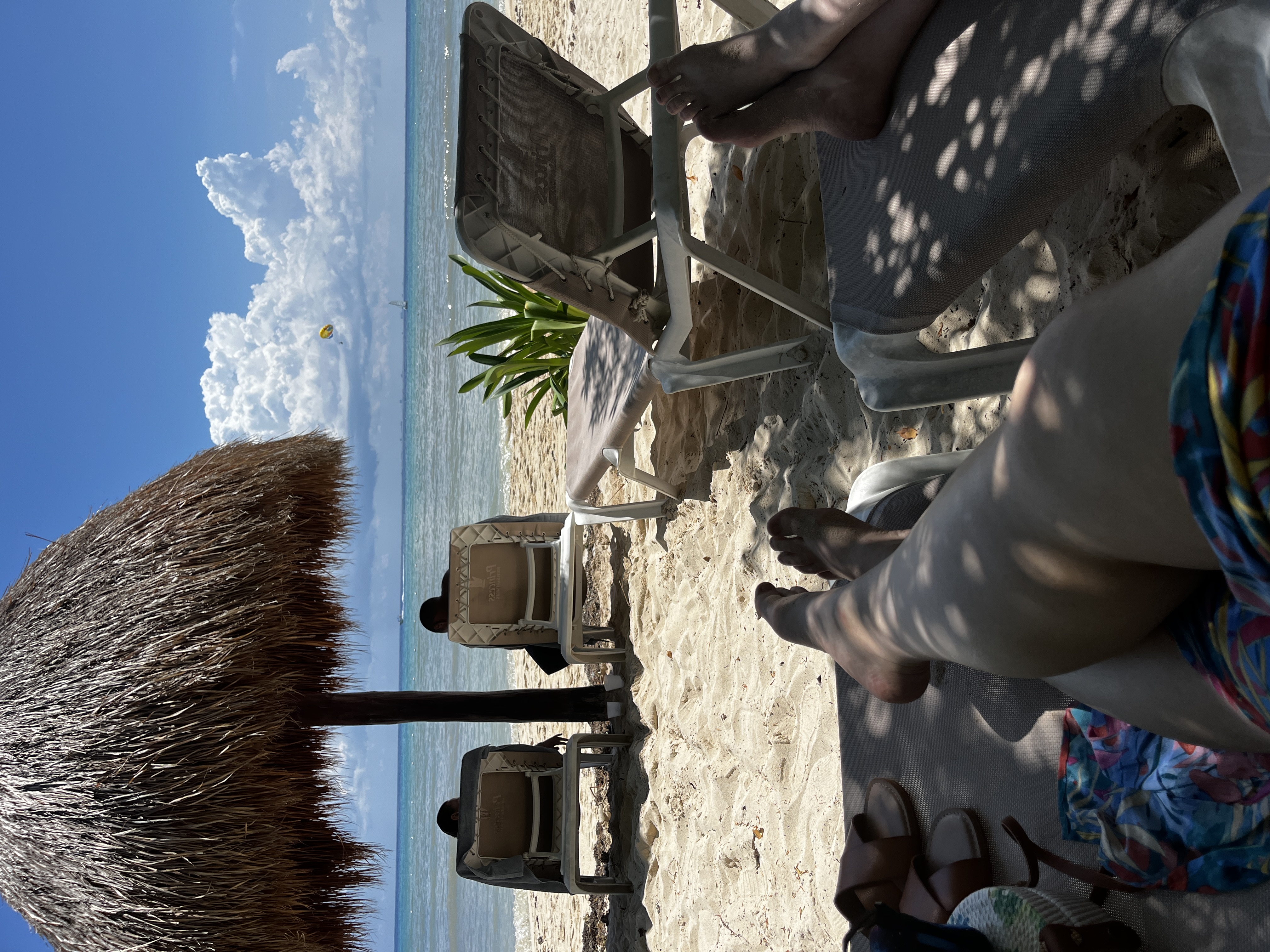 Advisor’s legs stretched out on a lounge chair in the shade on the beach