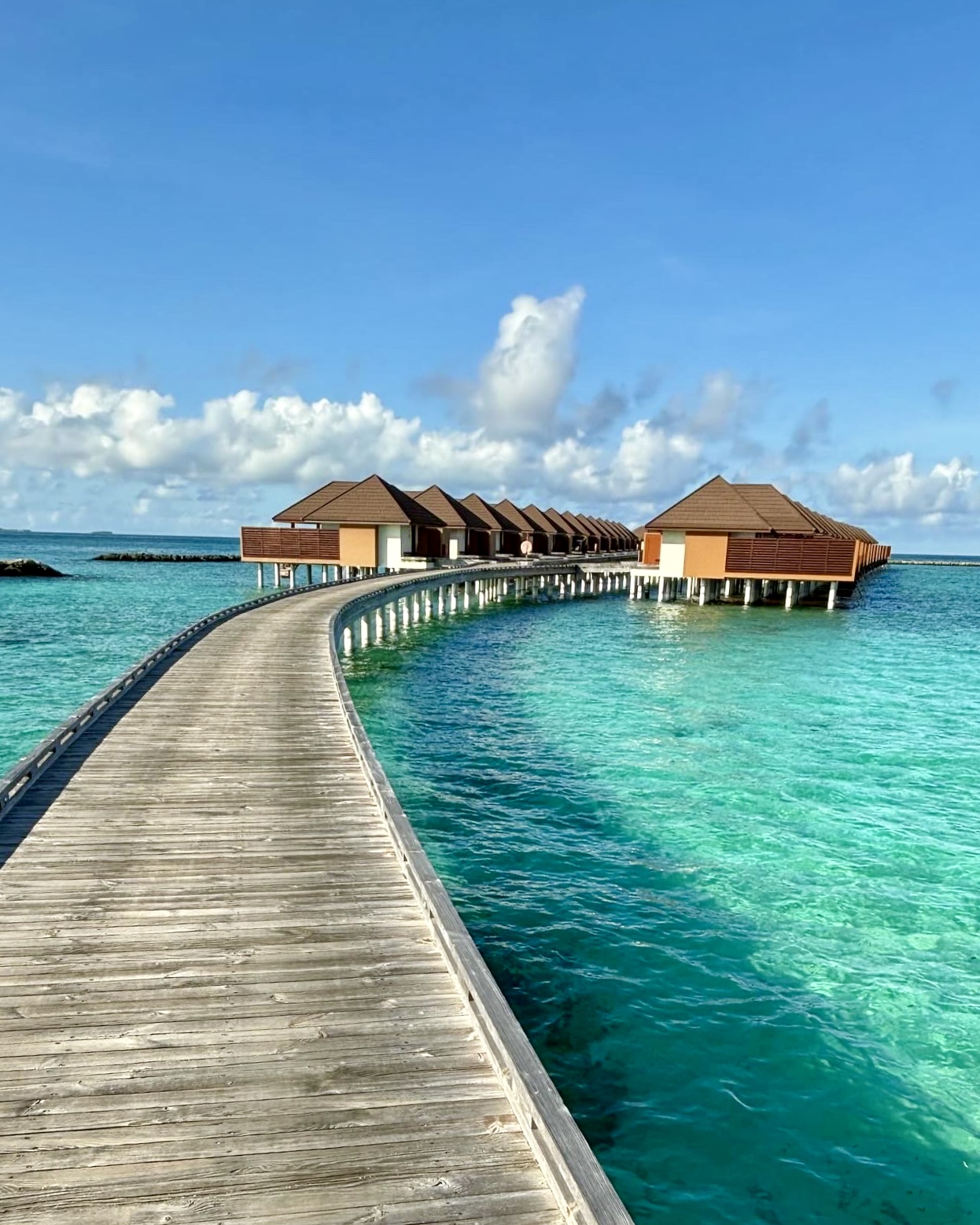 View of a wooden path leading to overwater bungalows on a sunny day