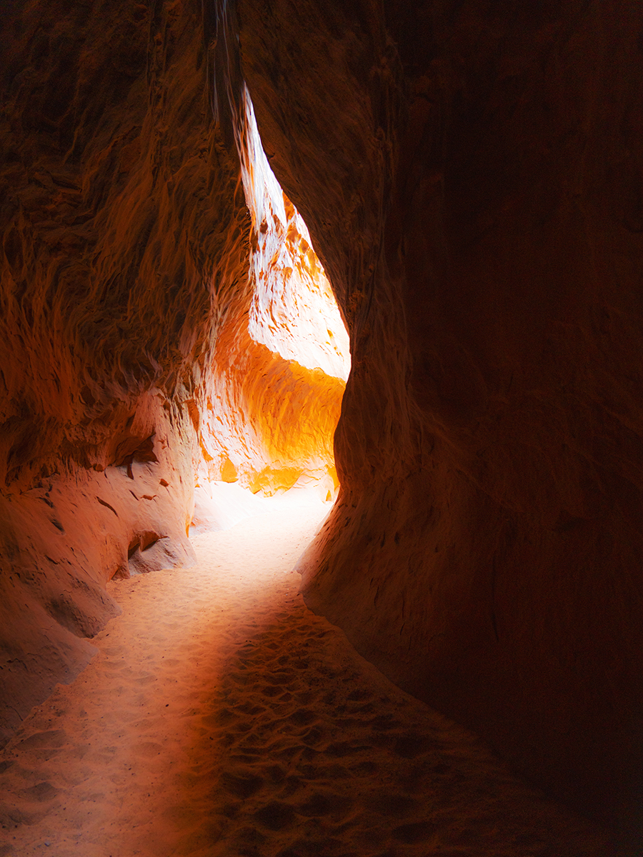 View of light coming through a crevice in a red rock canyon