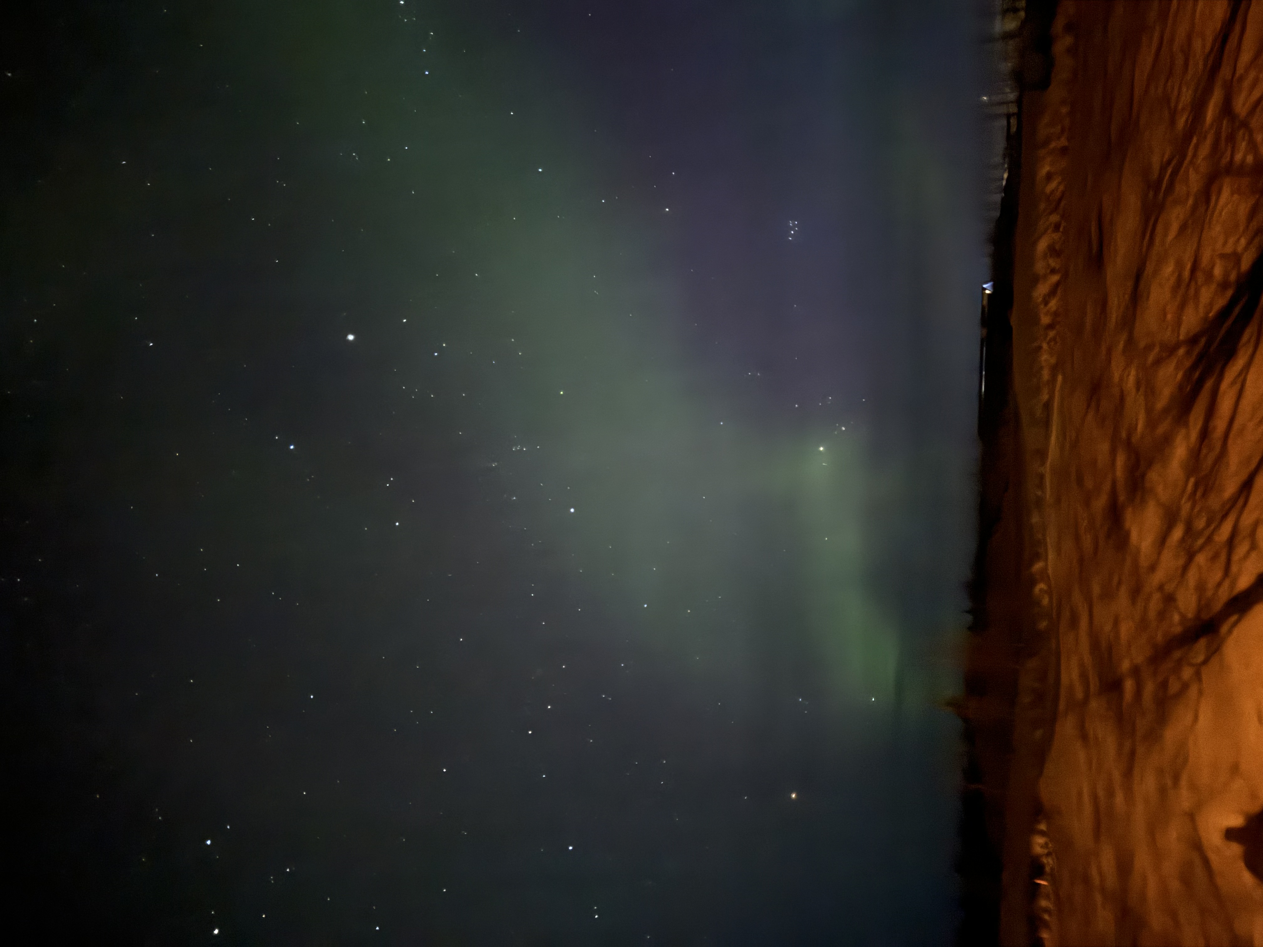 The Northern Lights glowing green in a starry night sky.