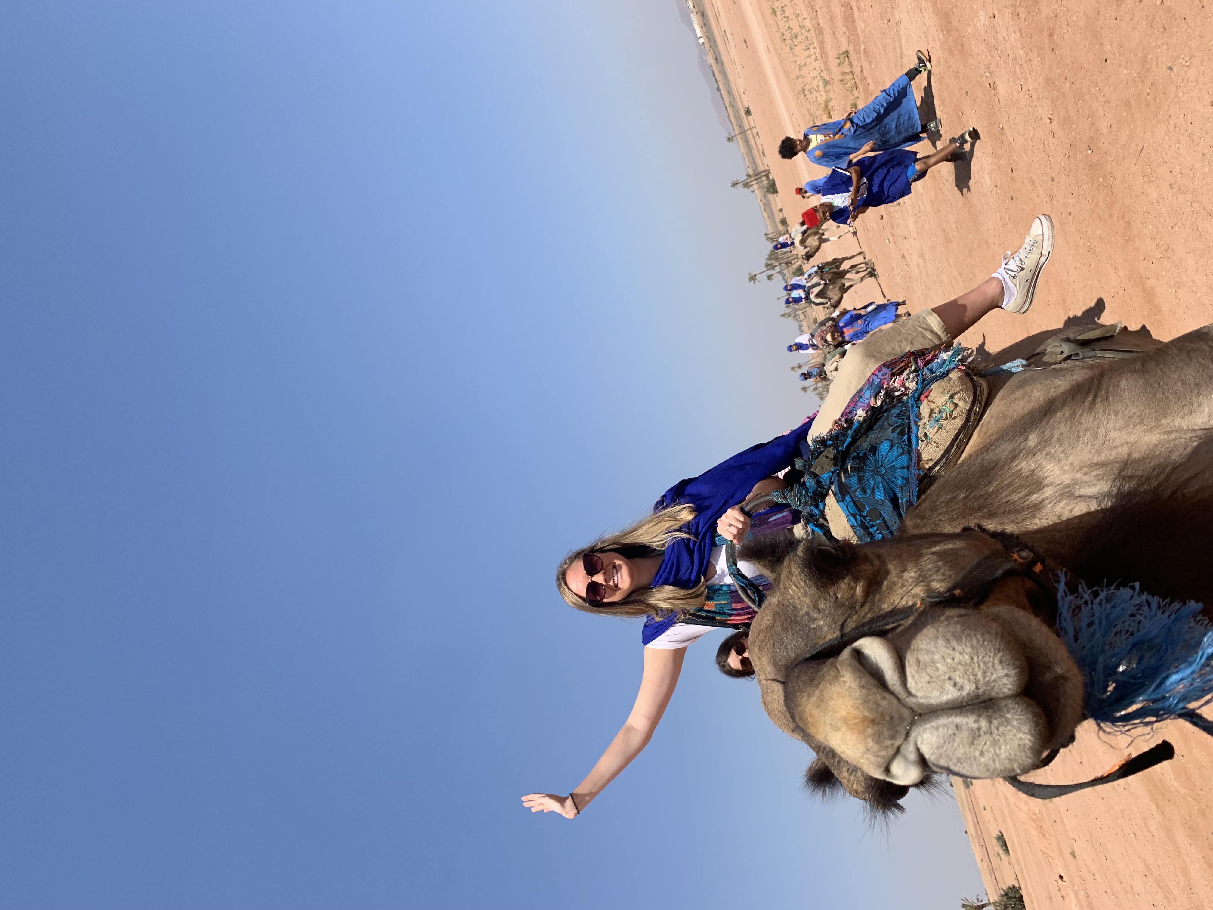 Advisor on camelback riding through the desert under clear skies