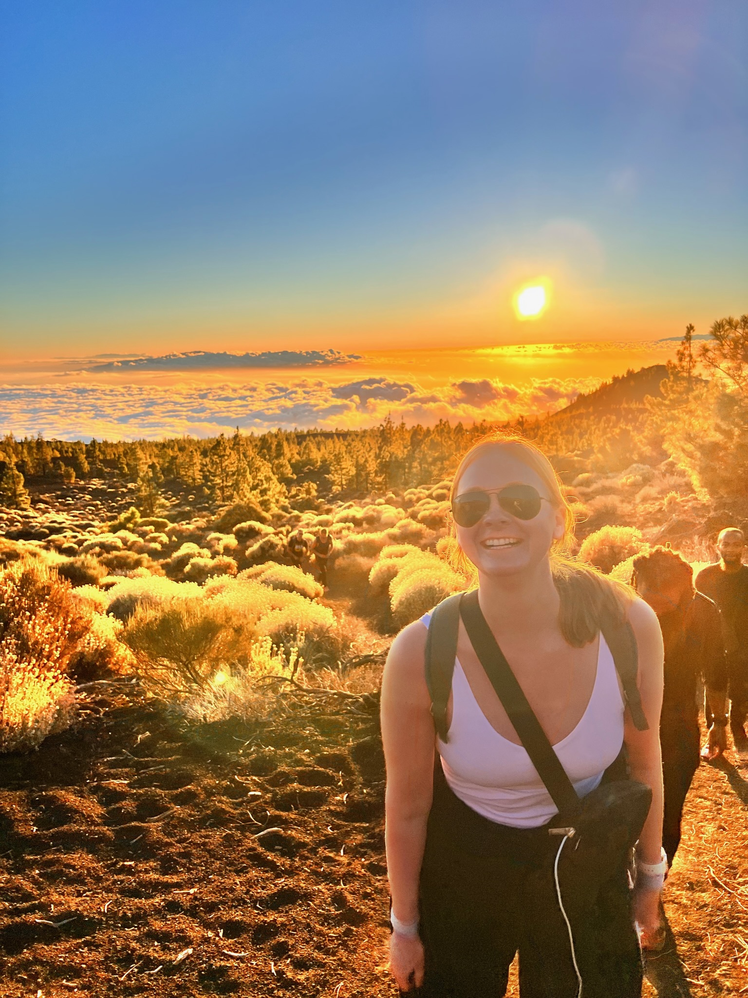 Advisor smiling on a sunset hike with her surroundings bathed in golden light