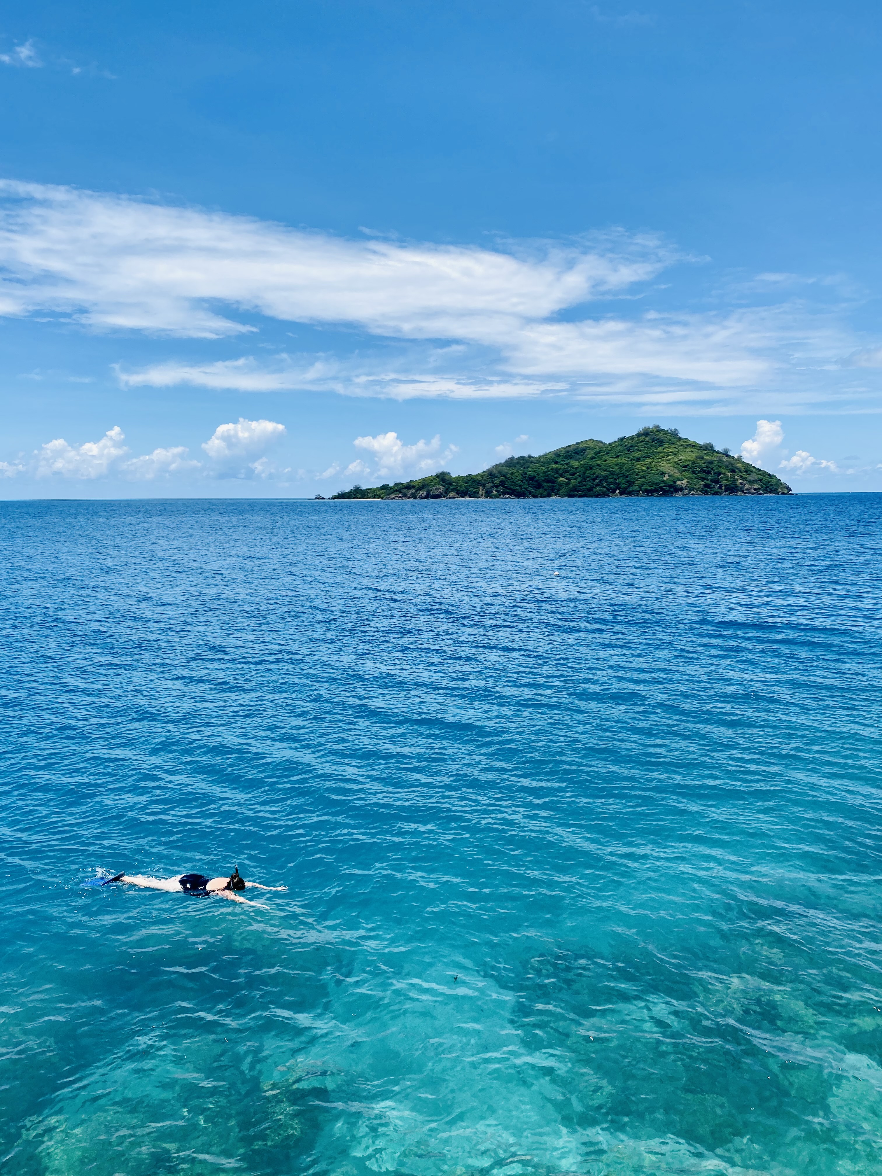A view of the ocean with an island in the distance on a sunny day.