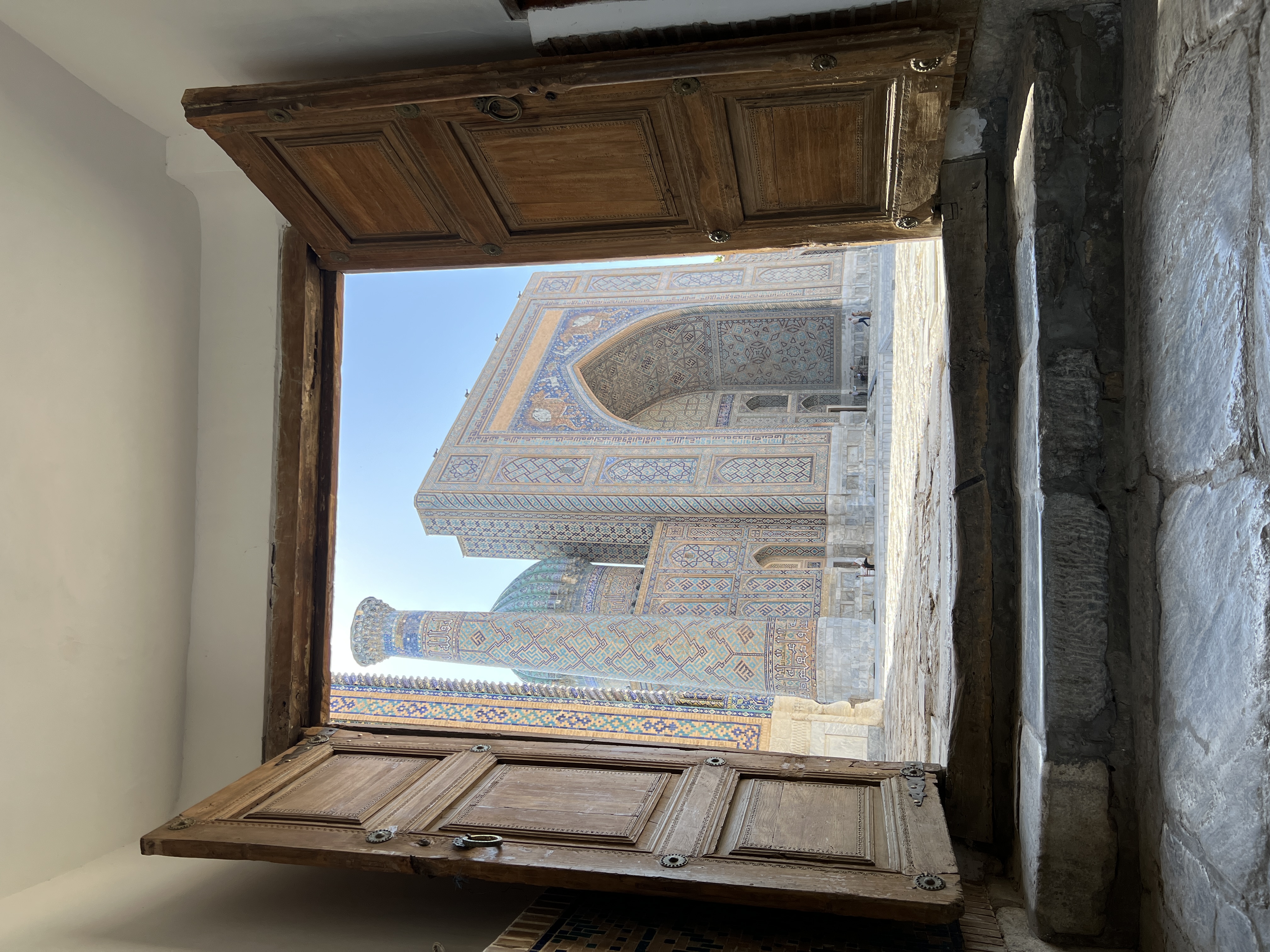 A view of a large mosaic building behind a set of large wooden doors.