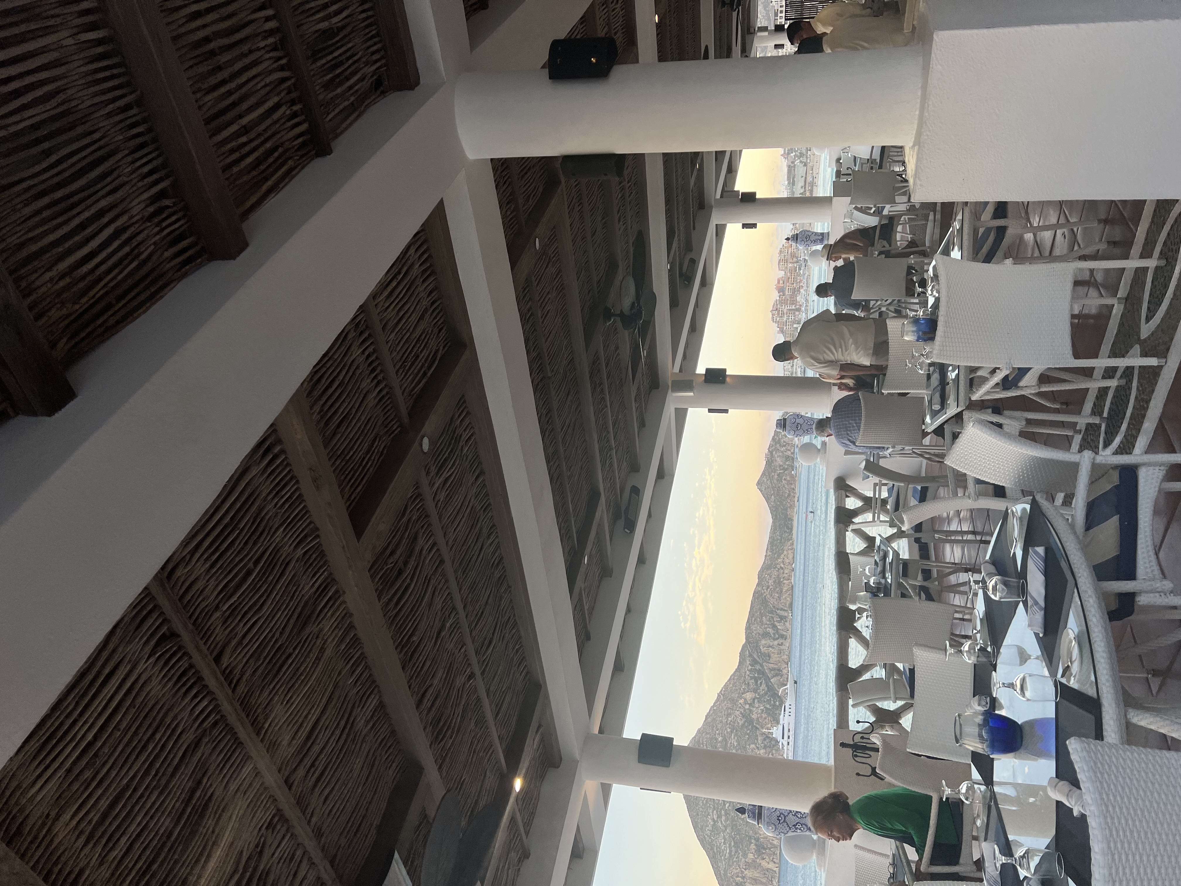 Inside of a restaurant with a view of the ocean in the background.