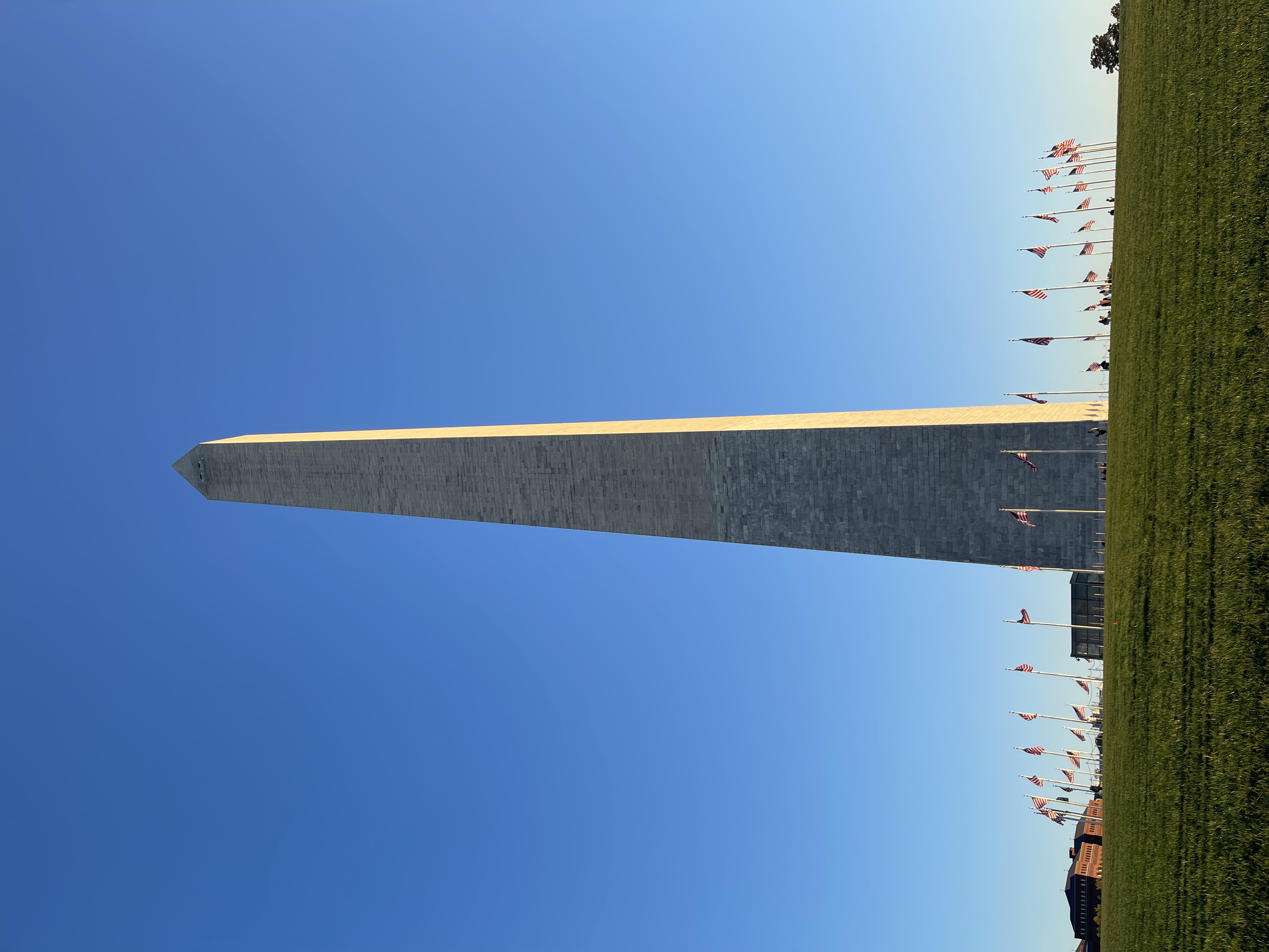 Close up view of the Washington Monument with small flags in a circular at its base on a clear day
