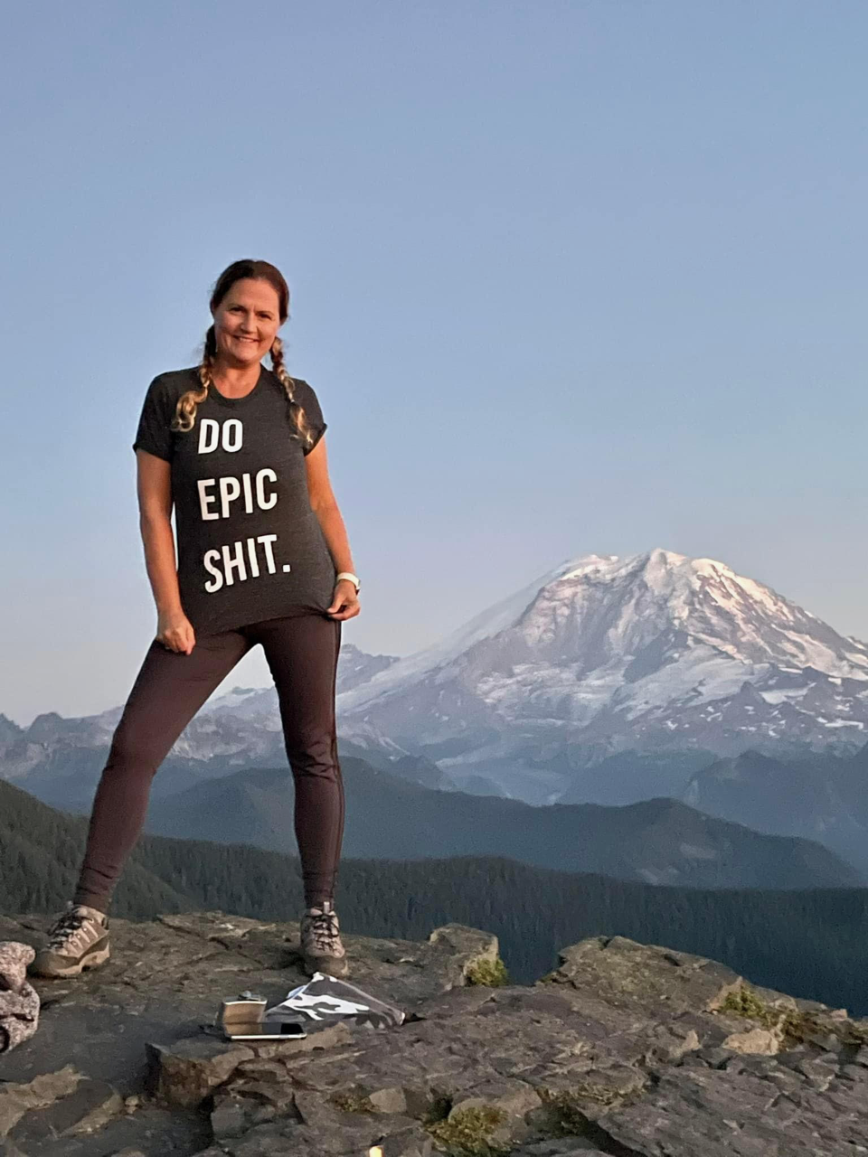 Julie posing on top of a mountain with mountains in the background.