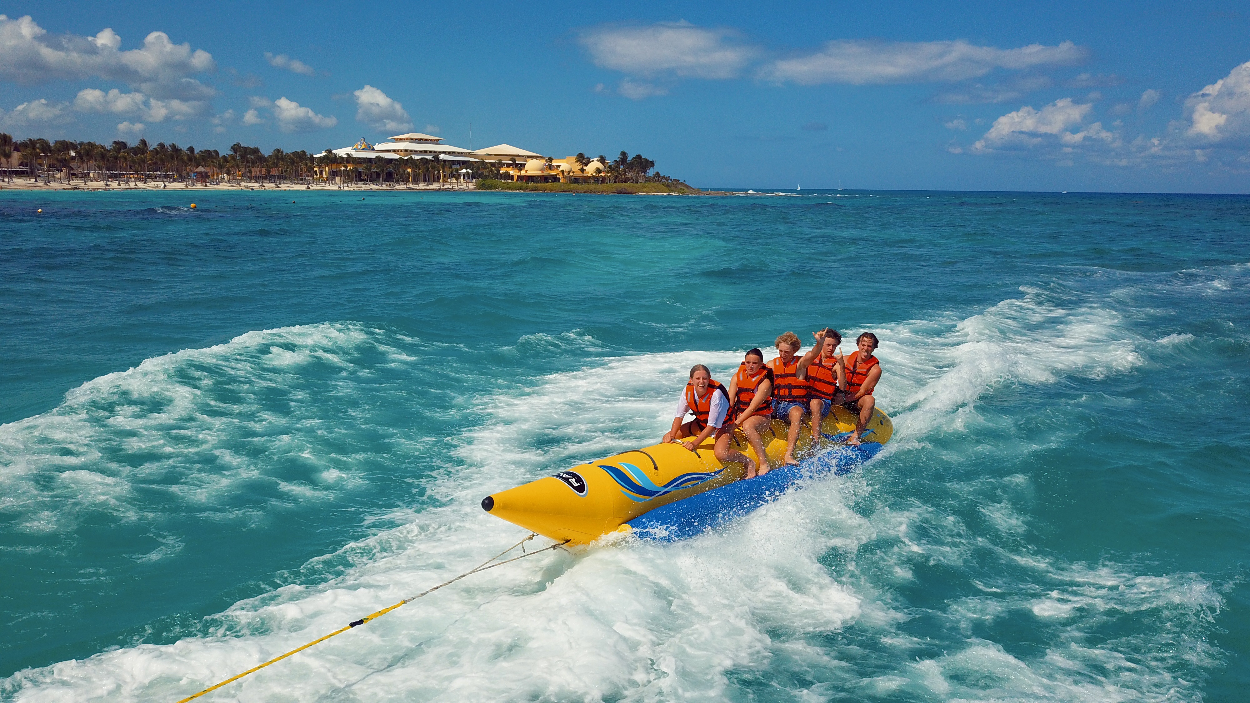 A group of individuals enjoying a thrilling ride on a banana boat, laughing and splashing in the water.