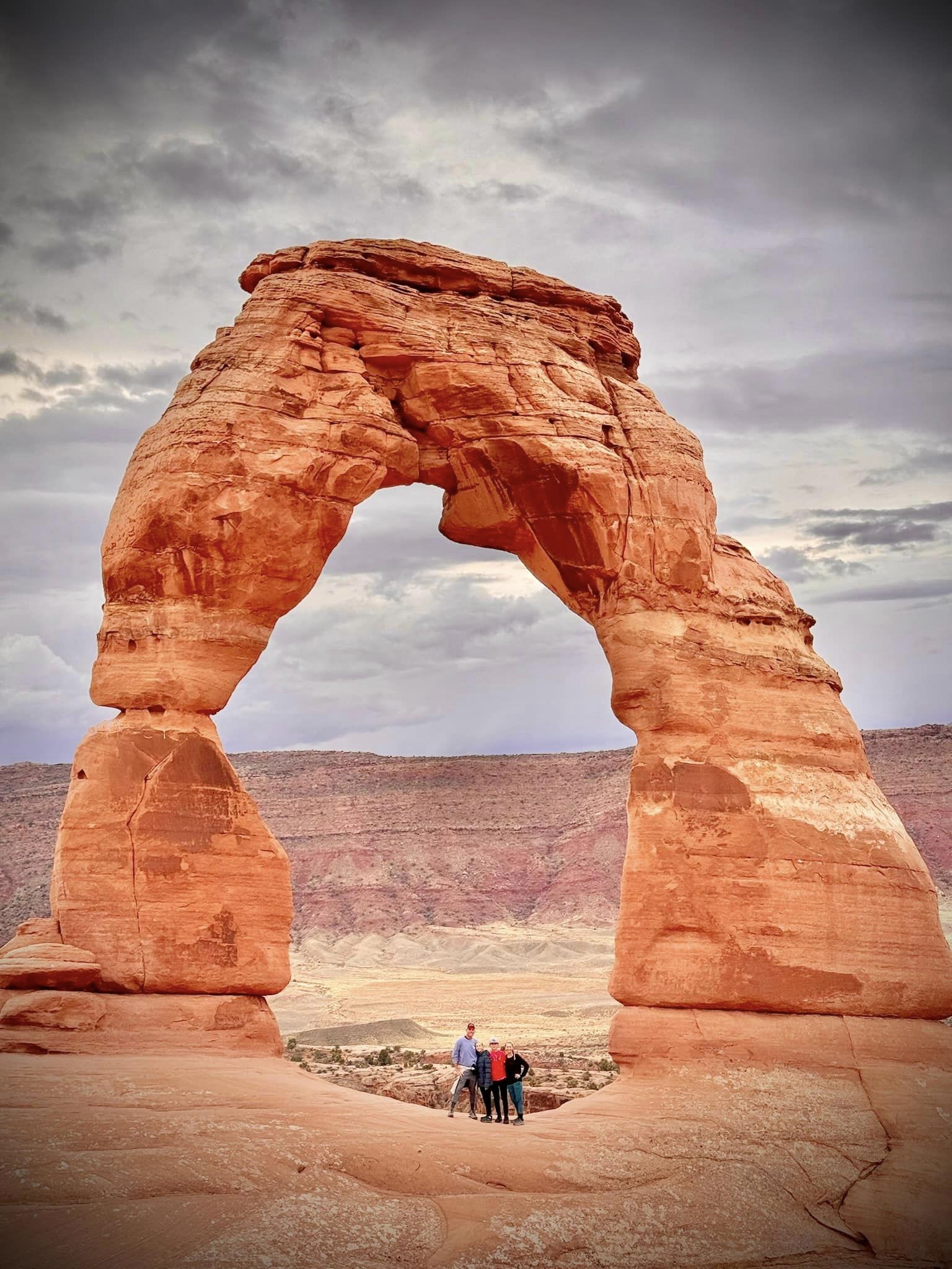 View of advisor and others underneath a large red rock stone arch formation