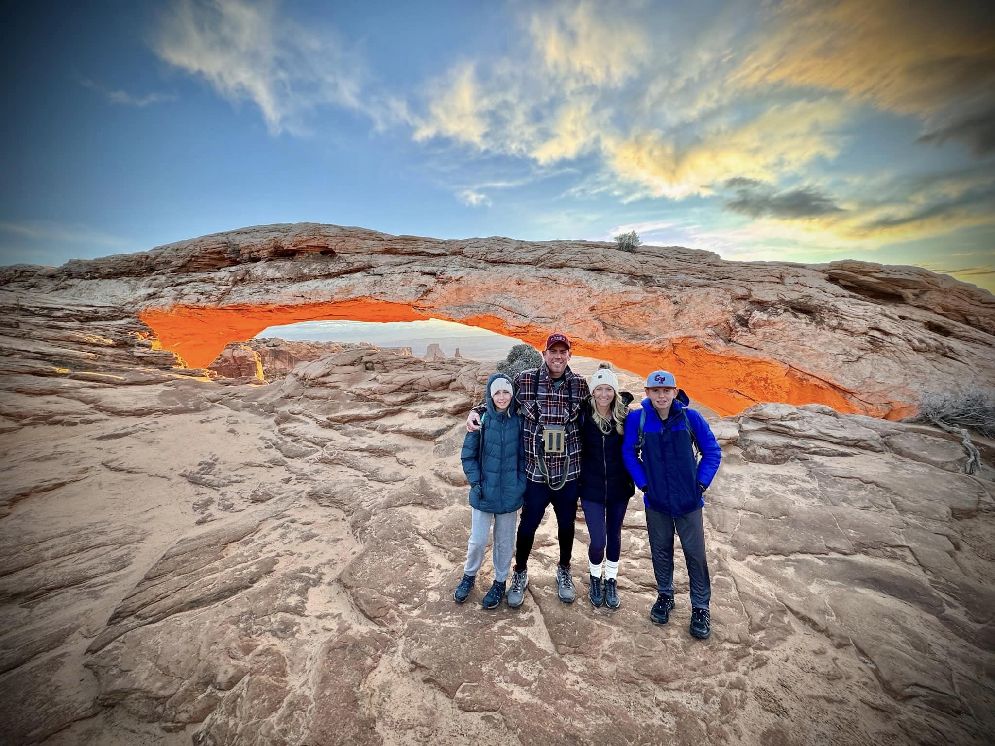 Advisor and family posing side by side on a mountaintop at sunset
