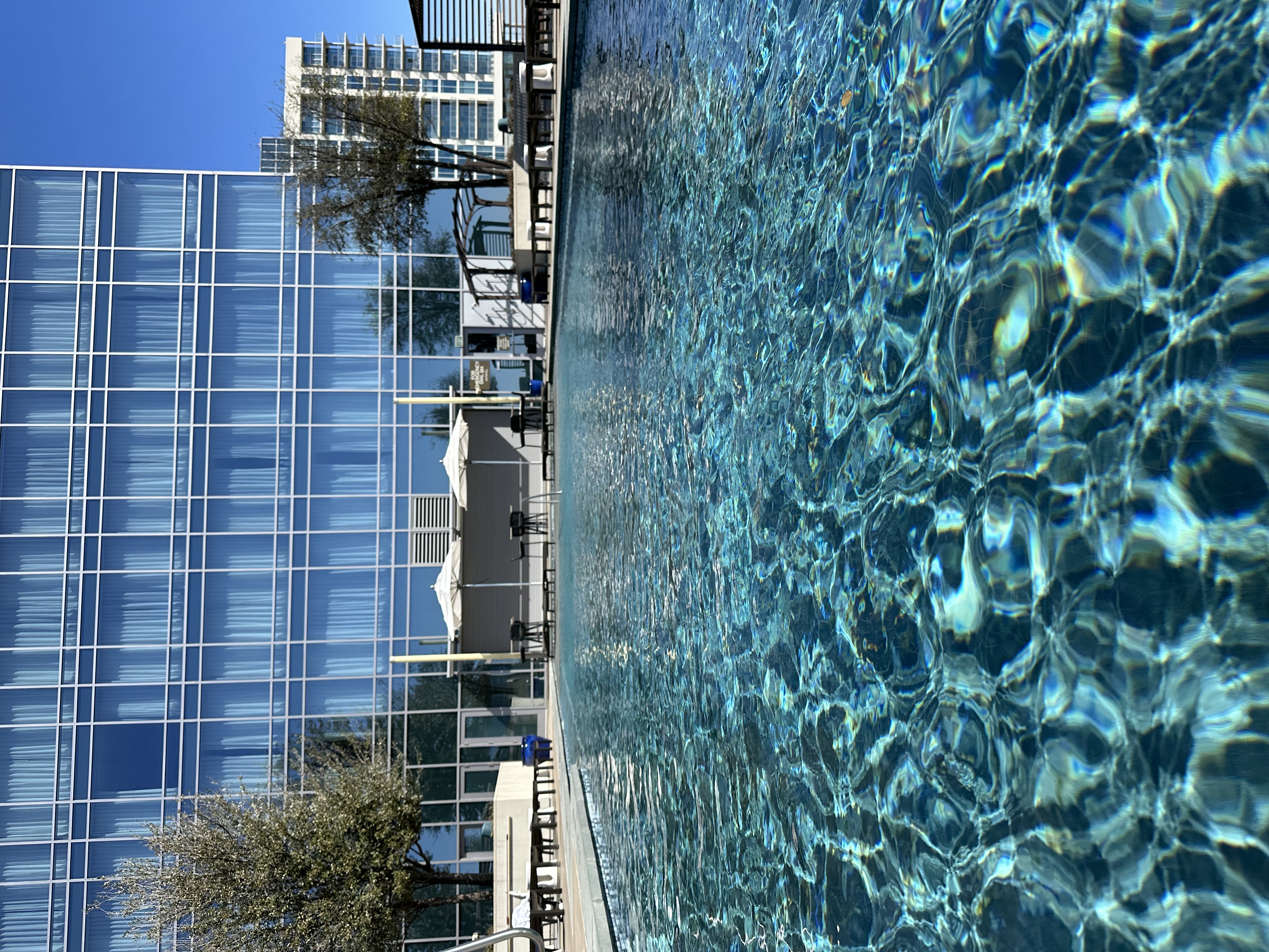 View of an empty resort pool with a glass building in the background