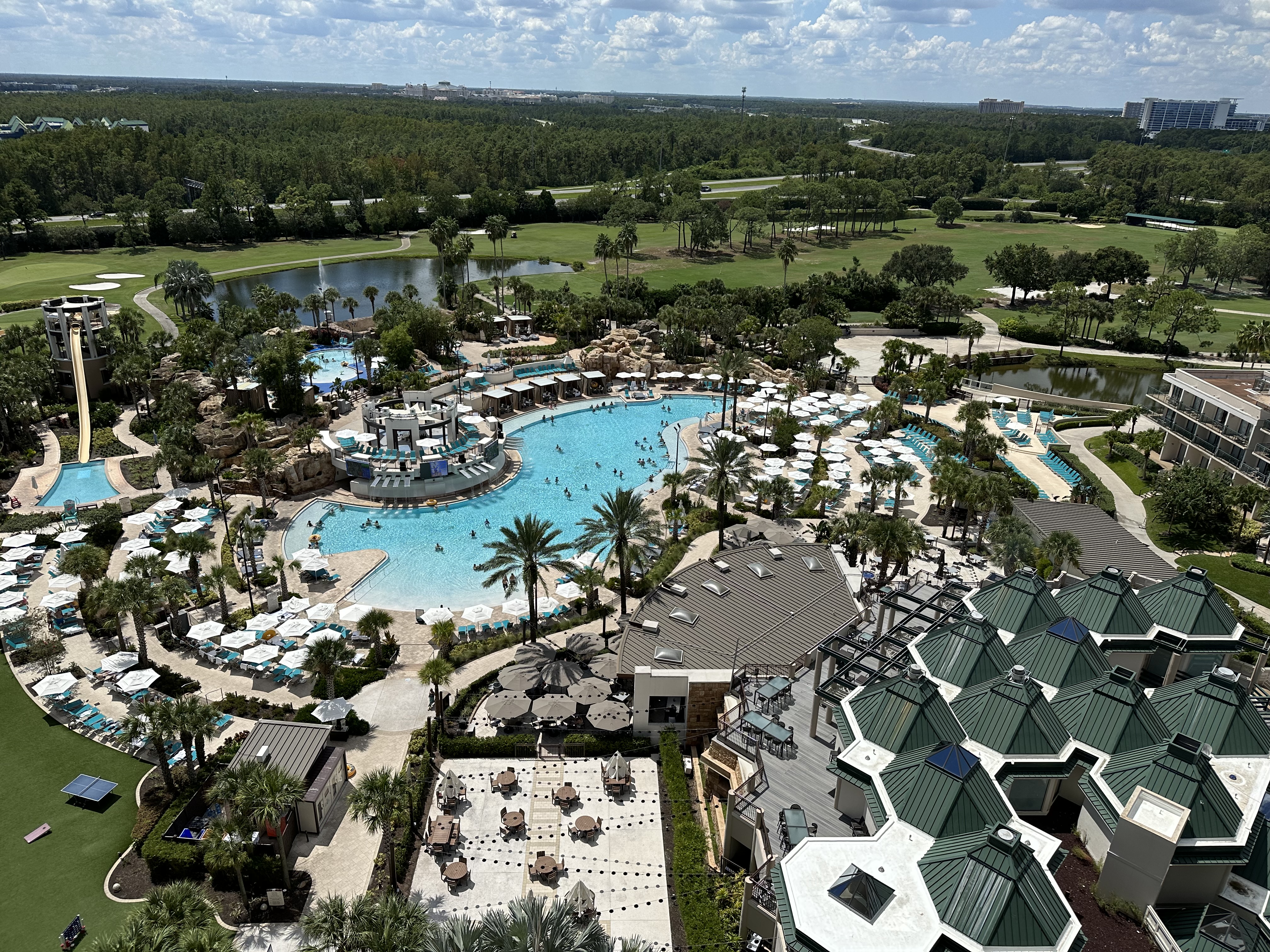 View of a large resort pool surrounded by umbrellas and lounge chairs