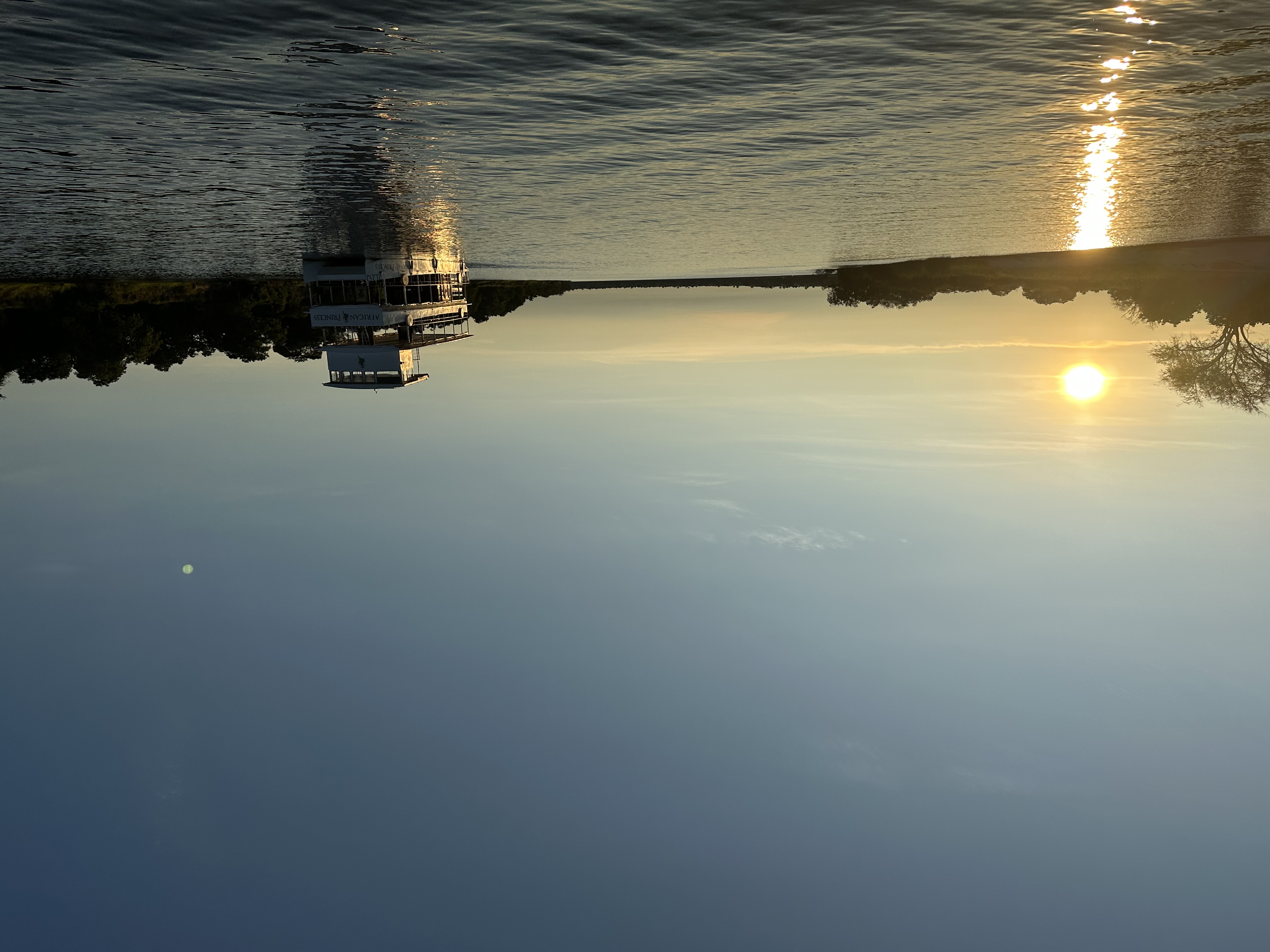 A view of a boat on a lake with the sun setting in the background.