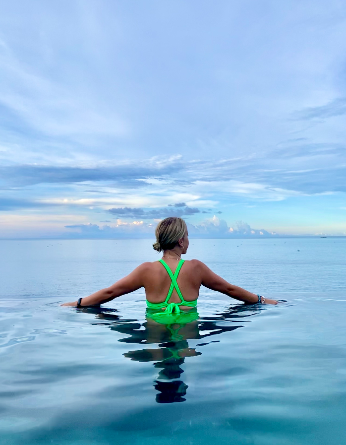 A person in a body of water outside during the daytime with their back to the camera