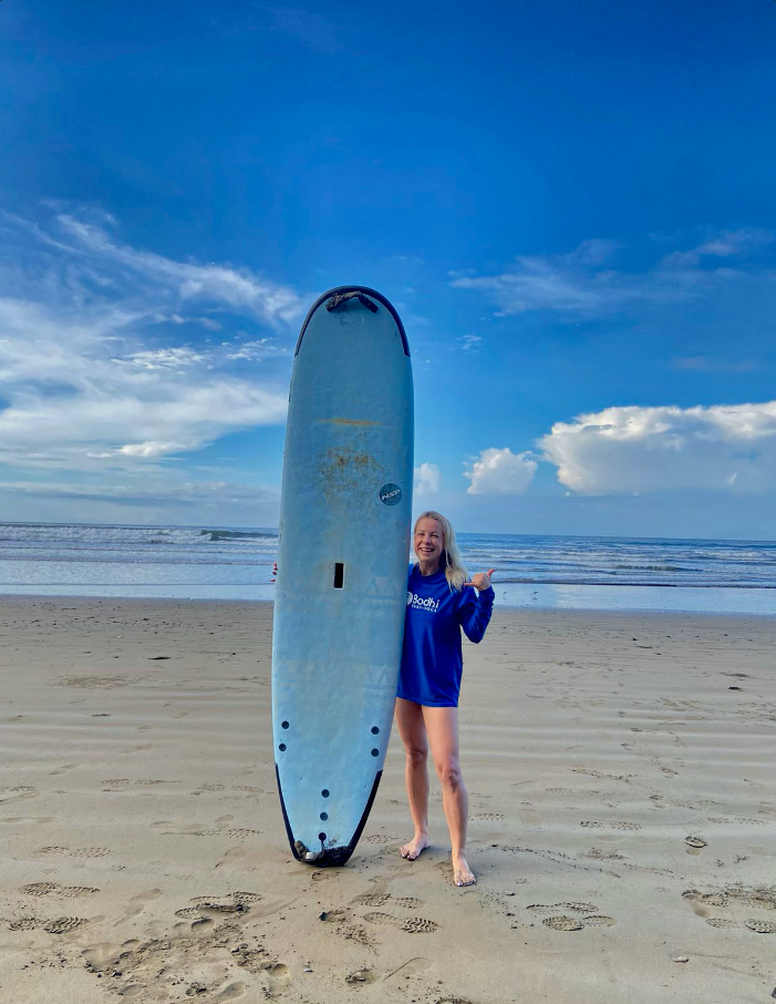A person holding a blue surfboard on the beach during the daytime