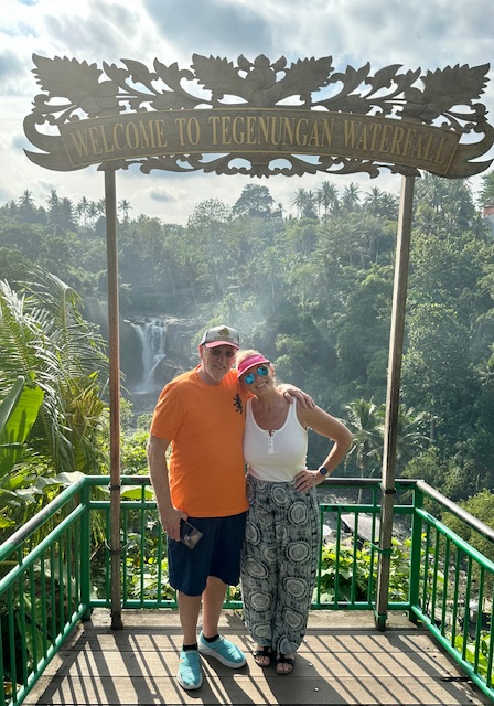 Advisor and partner standing side by side at a sign overlooking a waterfall in the jungle