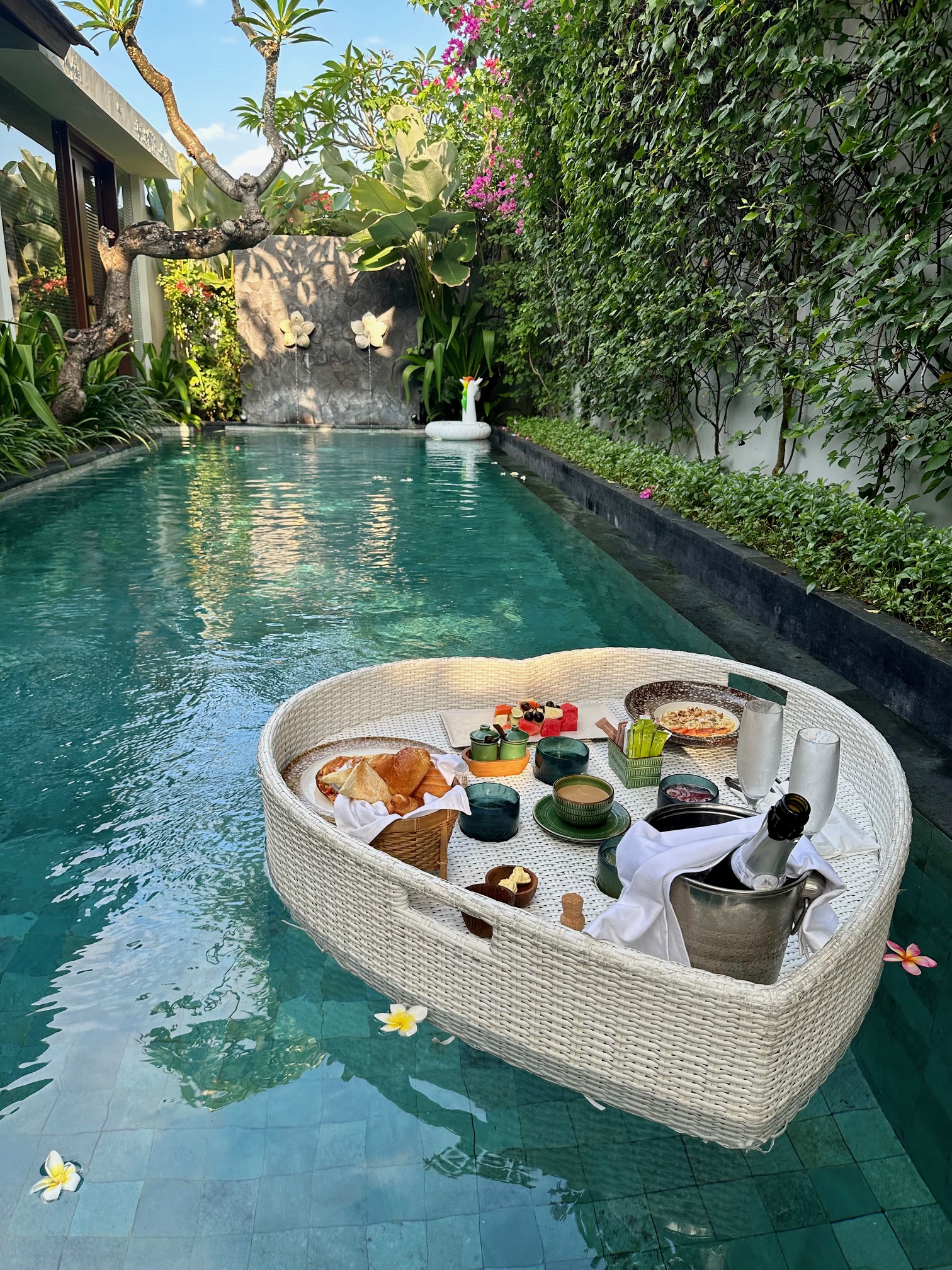 View of a floating breakfast spread in a private plunge pool surrounded by plants