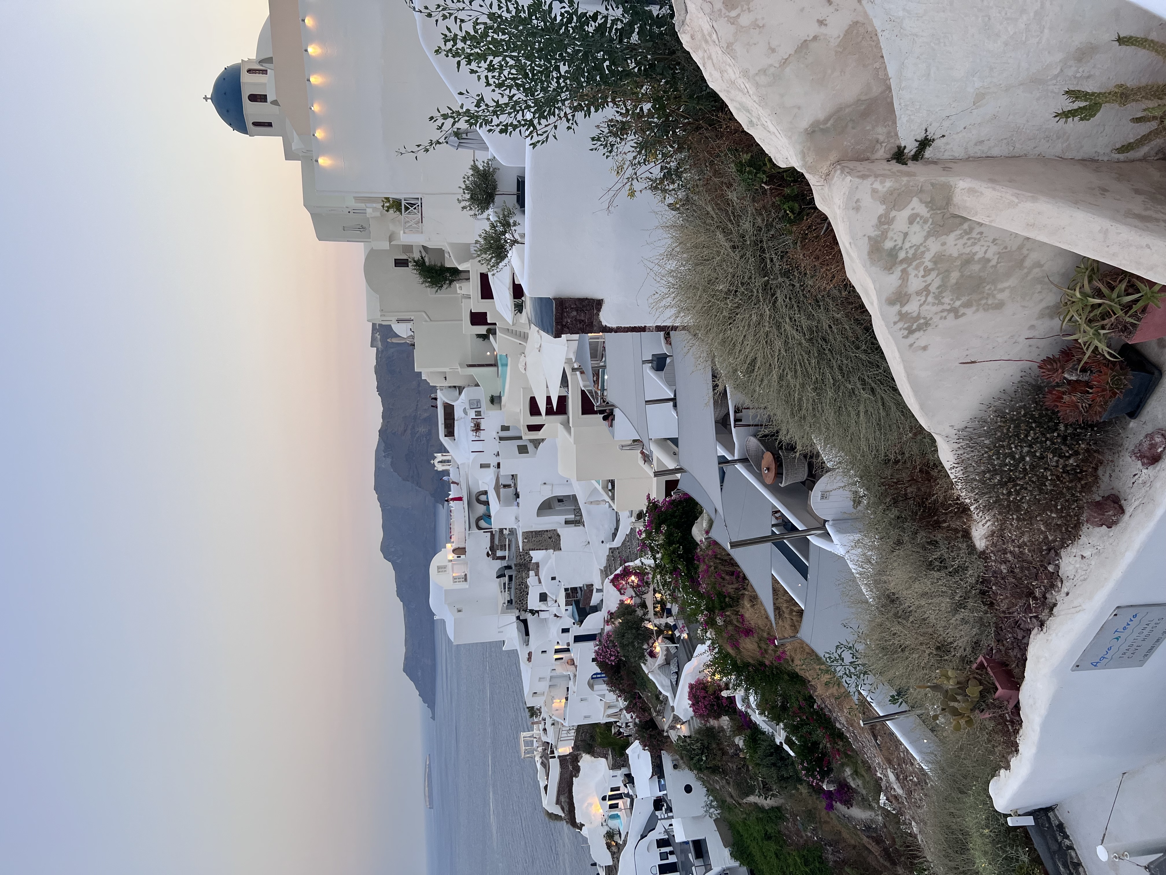 View of white buildings stretching to the coast in Santorini at sunset