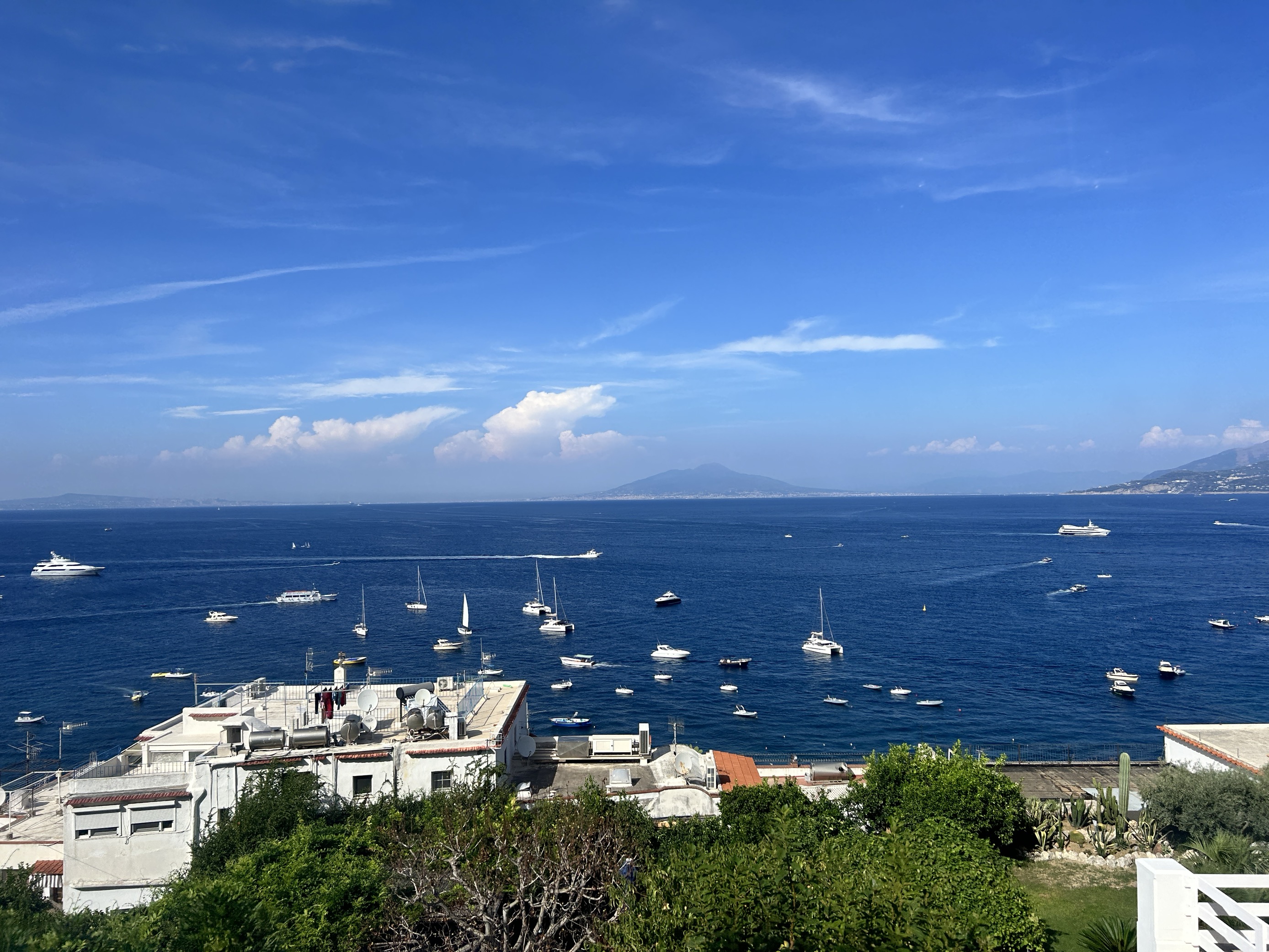 Aerial view of a harbor with boats docked offshore on a sunny day