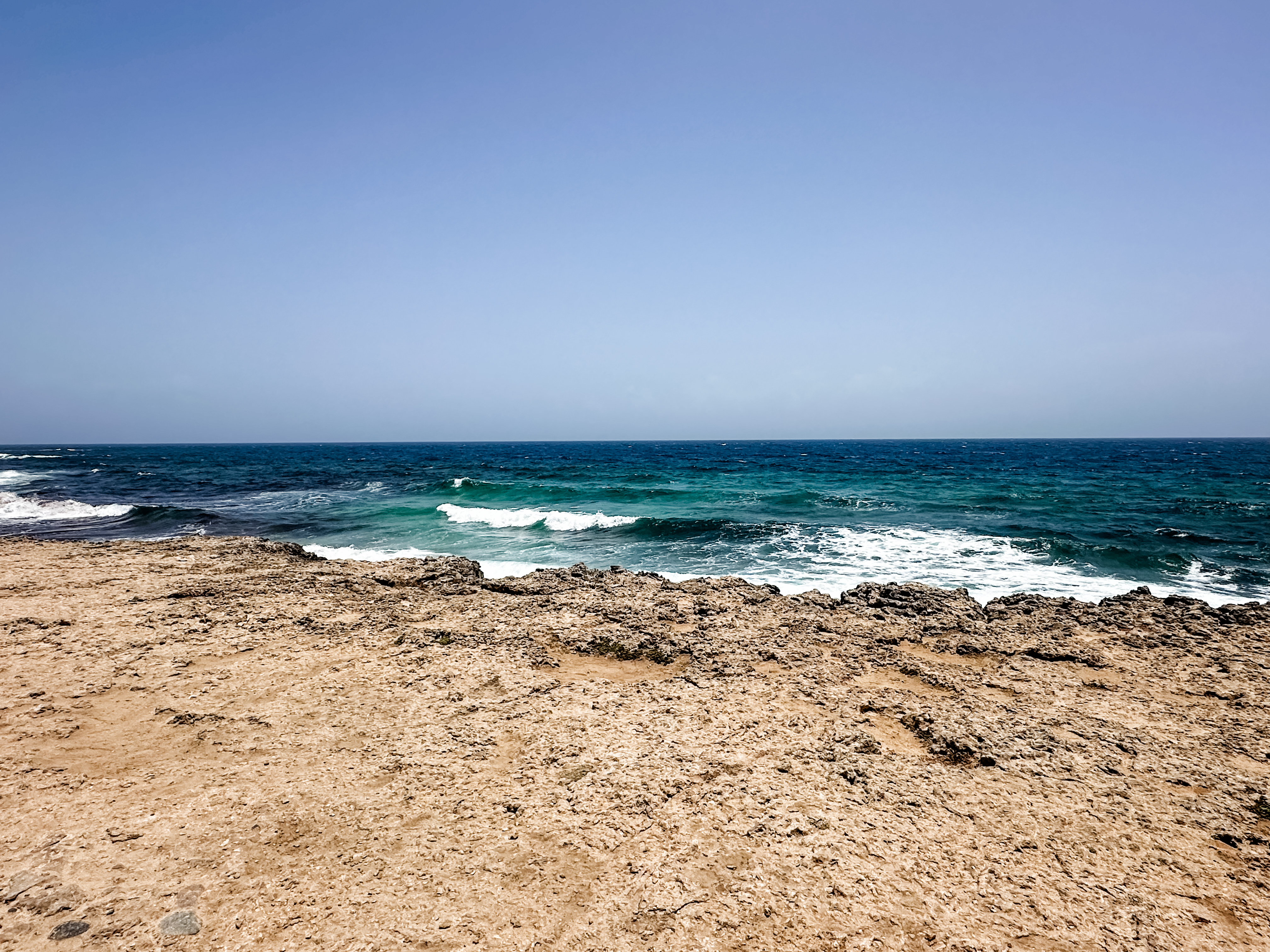 View of calm waves washing on ashore an empty beach under clear skies