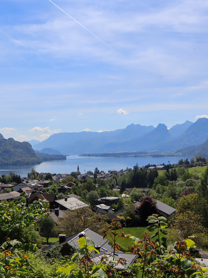 A clear blue sky adorned with fluffy white clouds, with a town beneath them.