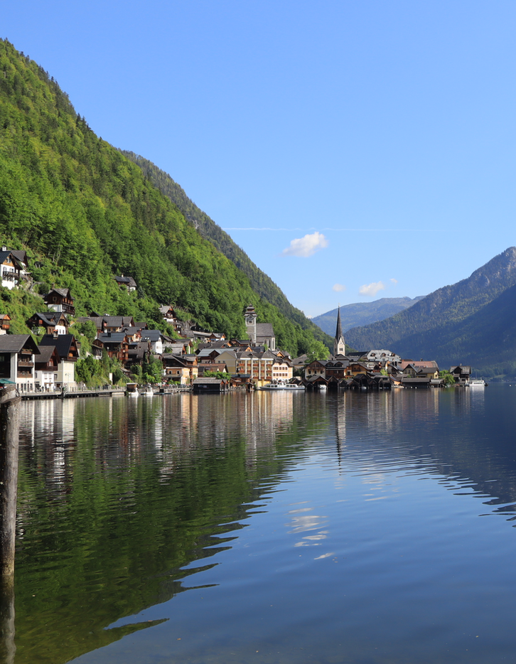 View of a lake with a town in the background with hills and mountains in the background.