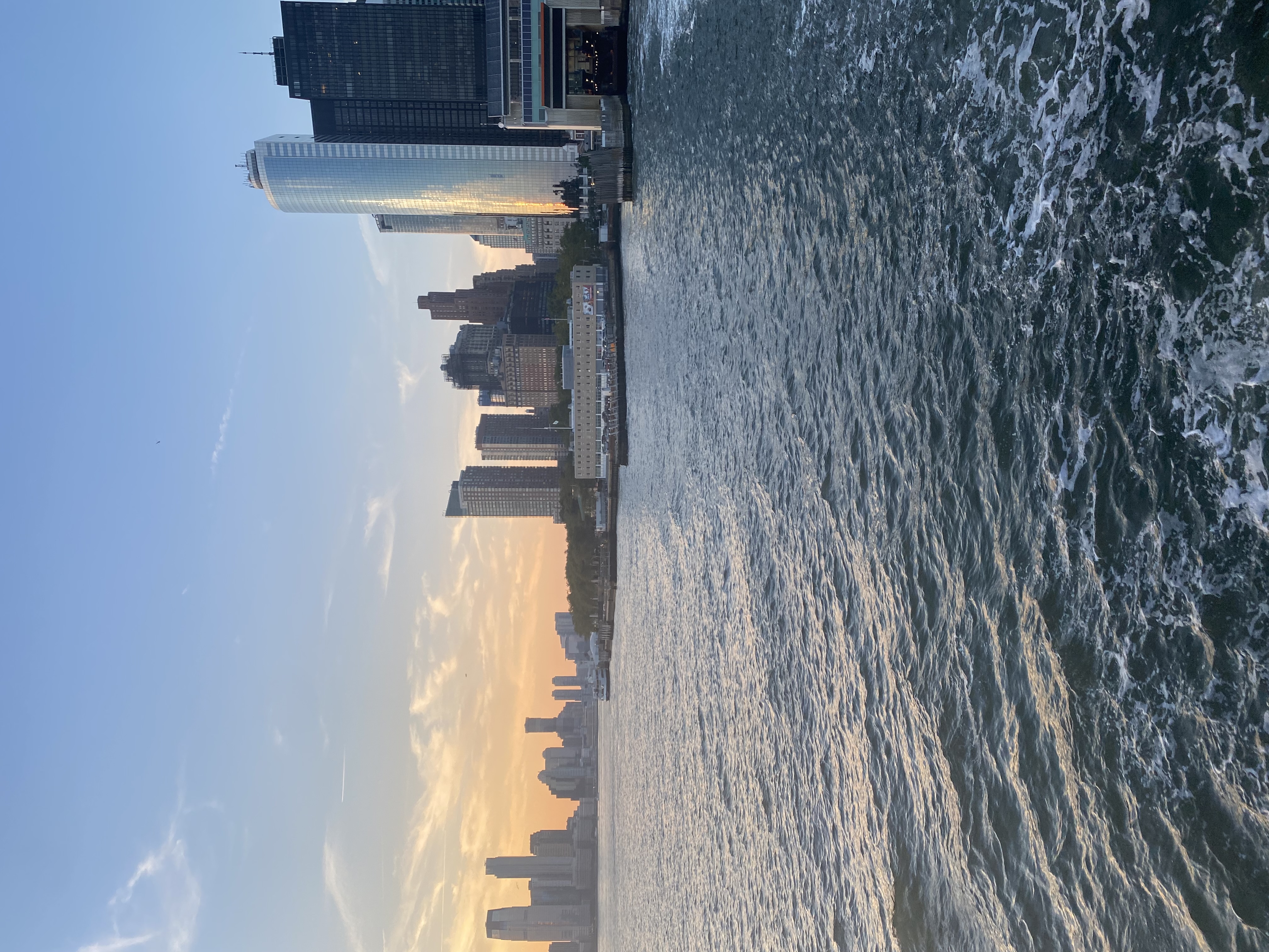 View of a river and the downtown New York City skyline at sunset