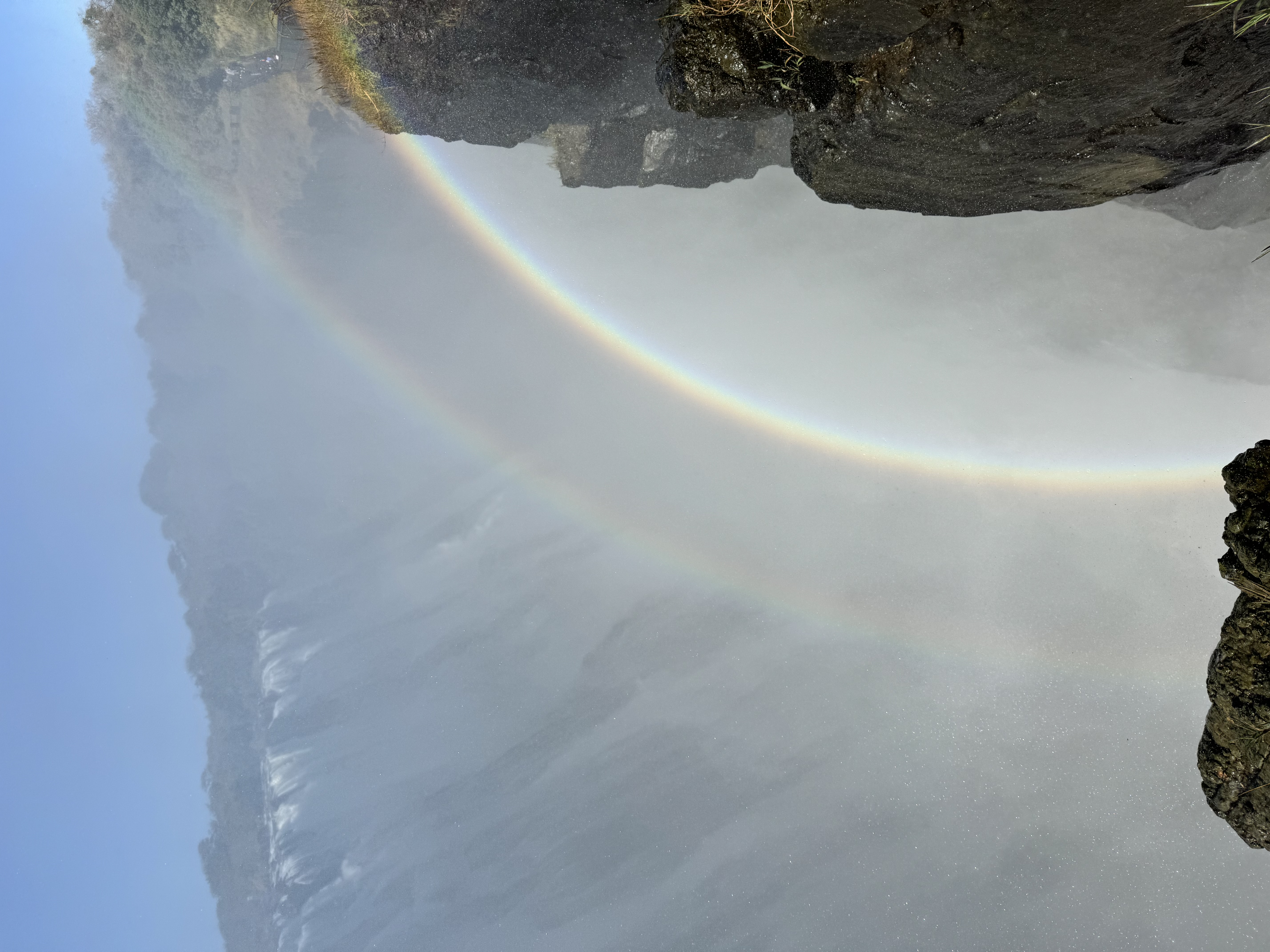 View of a beautiful rainbow formed by the mist of a waterfall