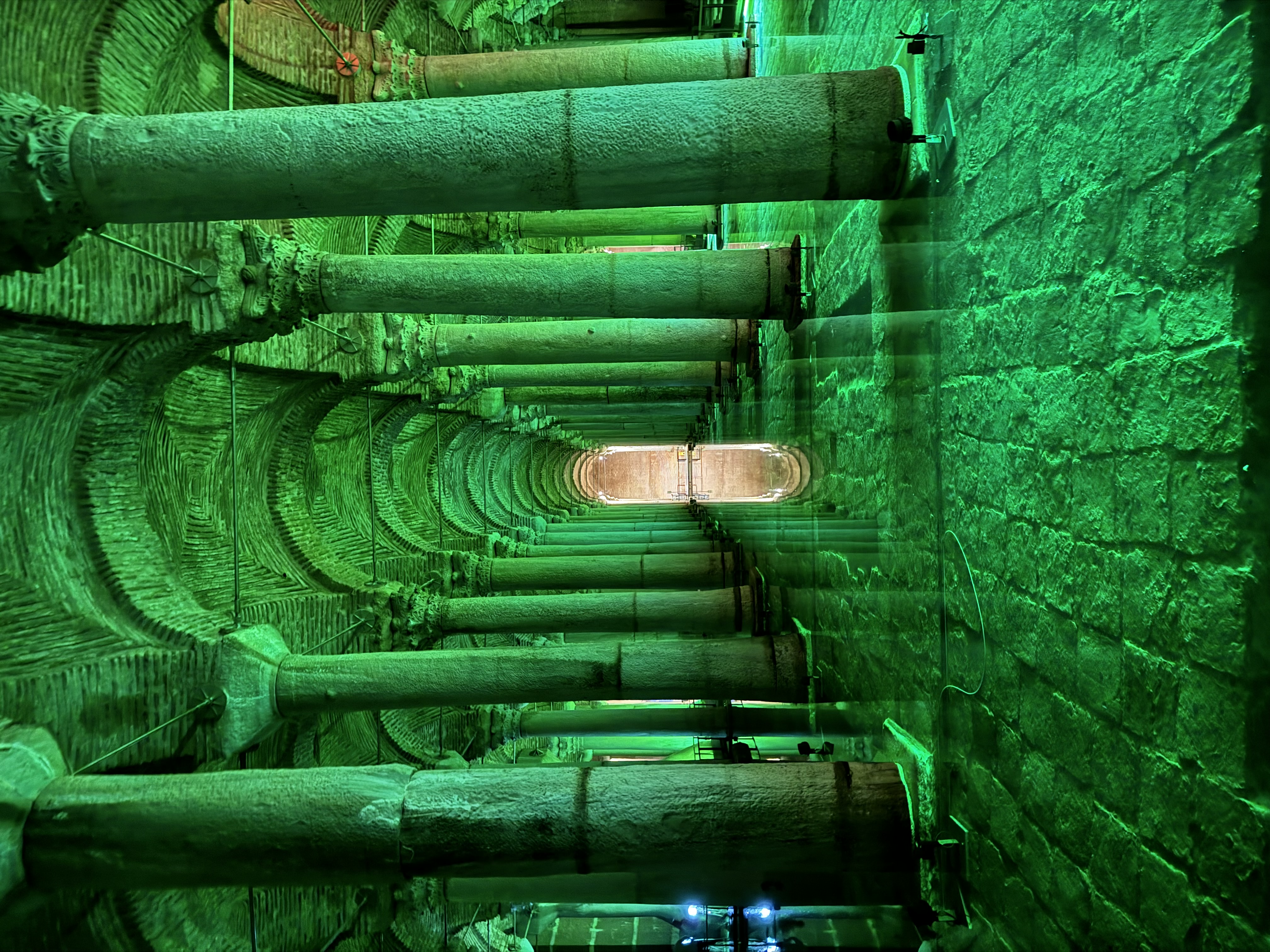 View of an old hall lined with columns and lit with green light