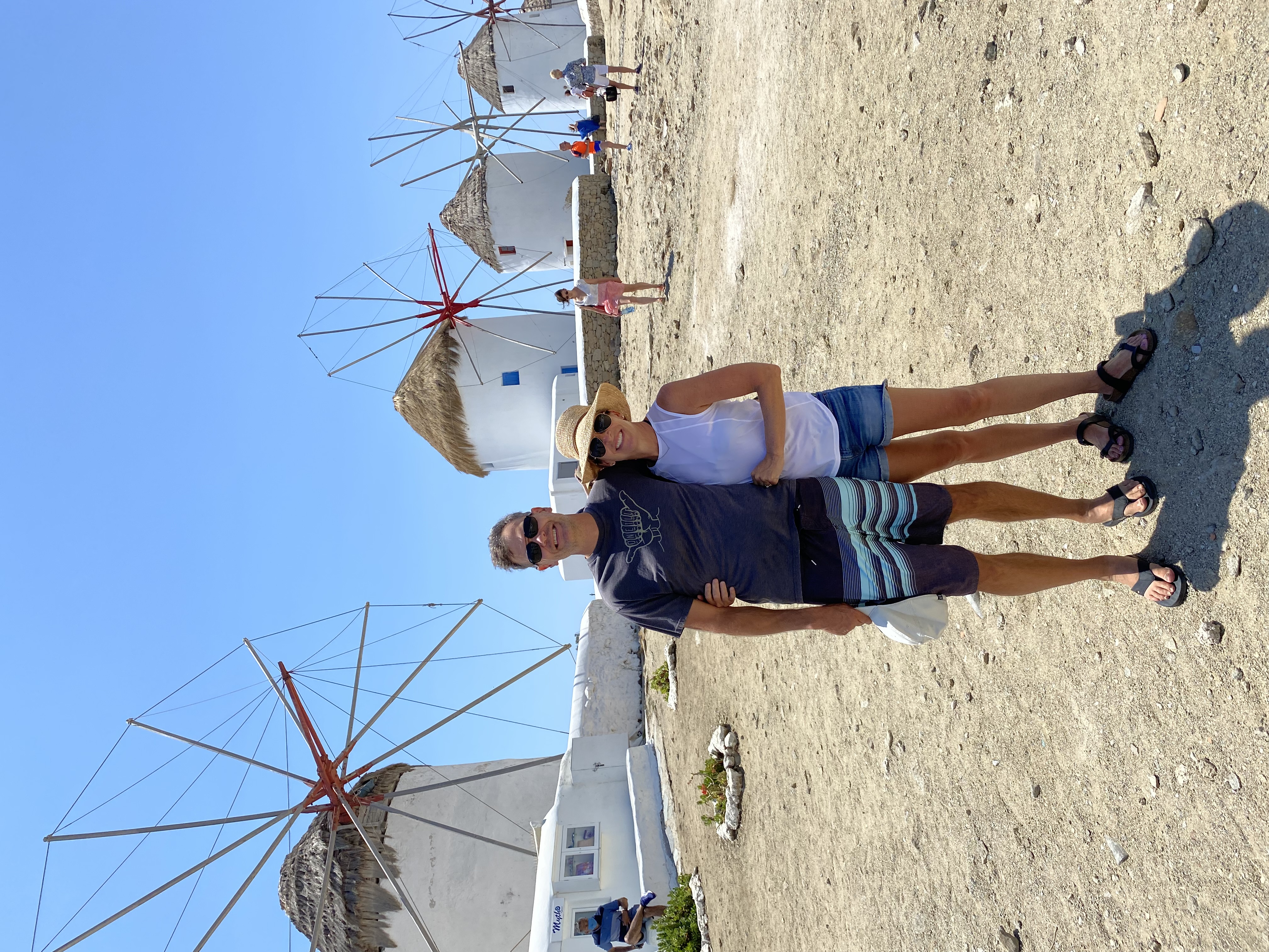 Advisor and partner standing side by side with old white windmills in a line behind them