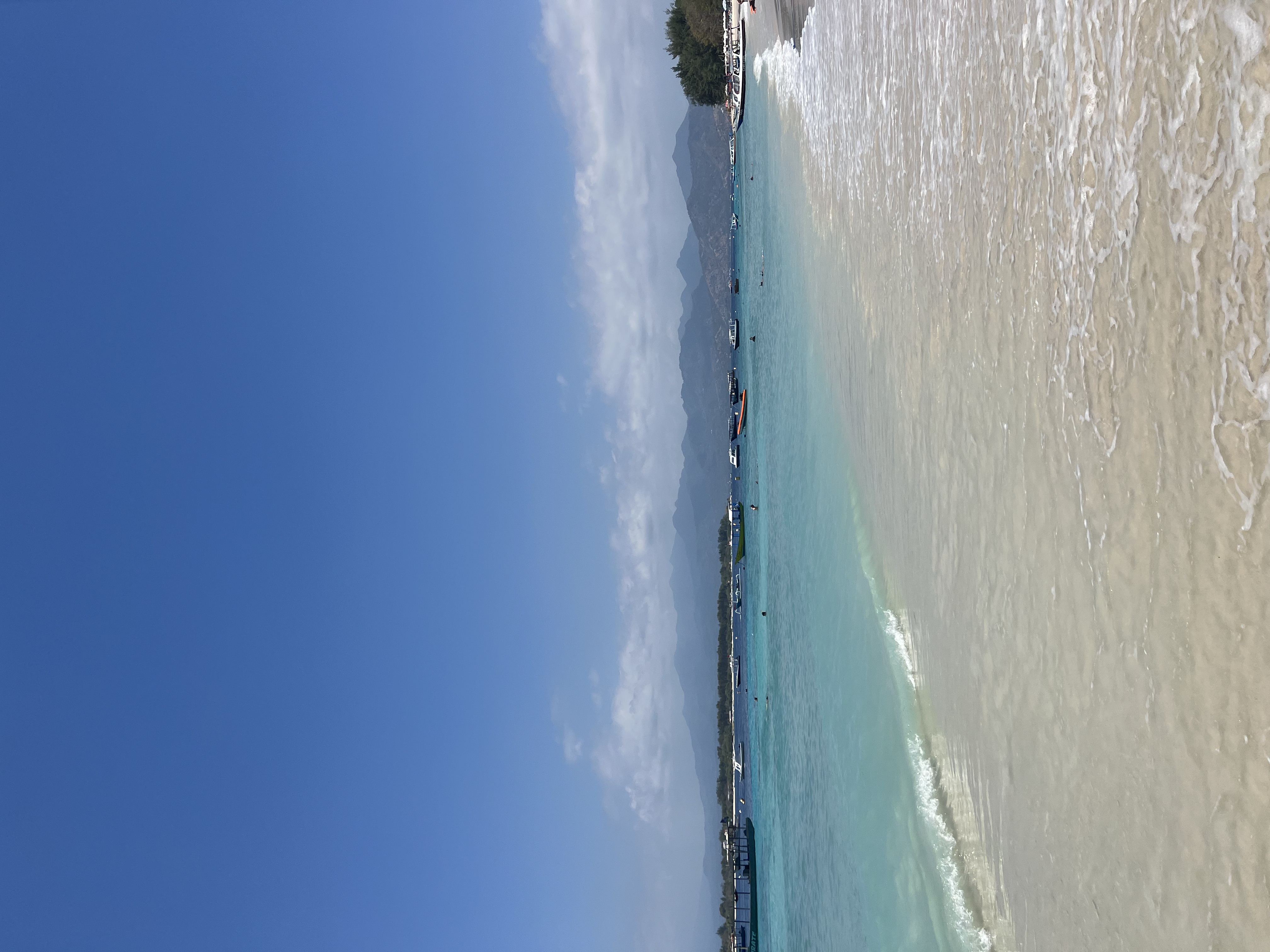 View of a calm white sand beach under clear skies