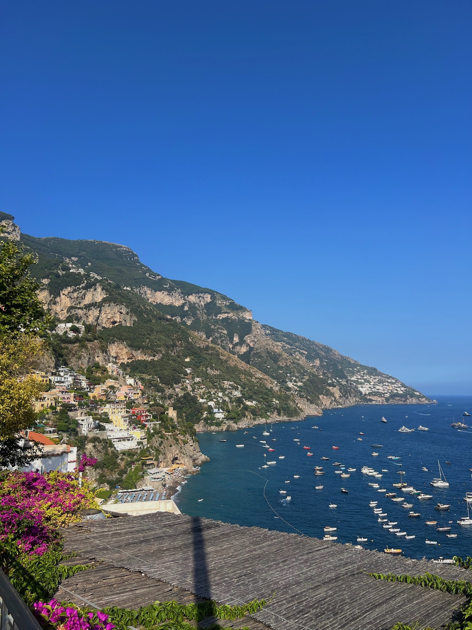 A cliffside scene with multiple boats in a body of water during the daytime