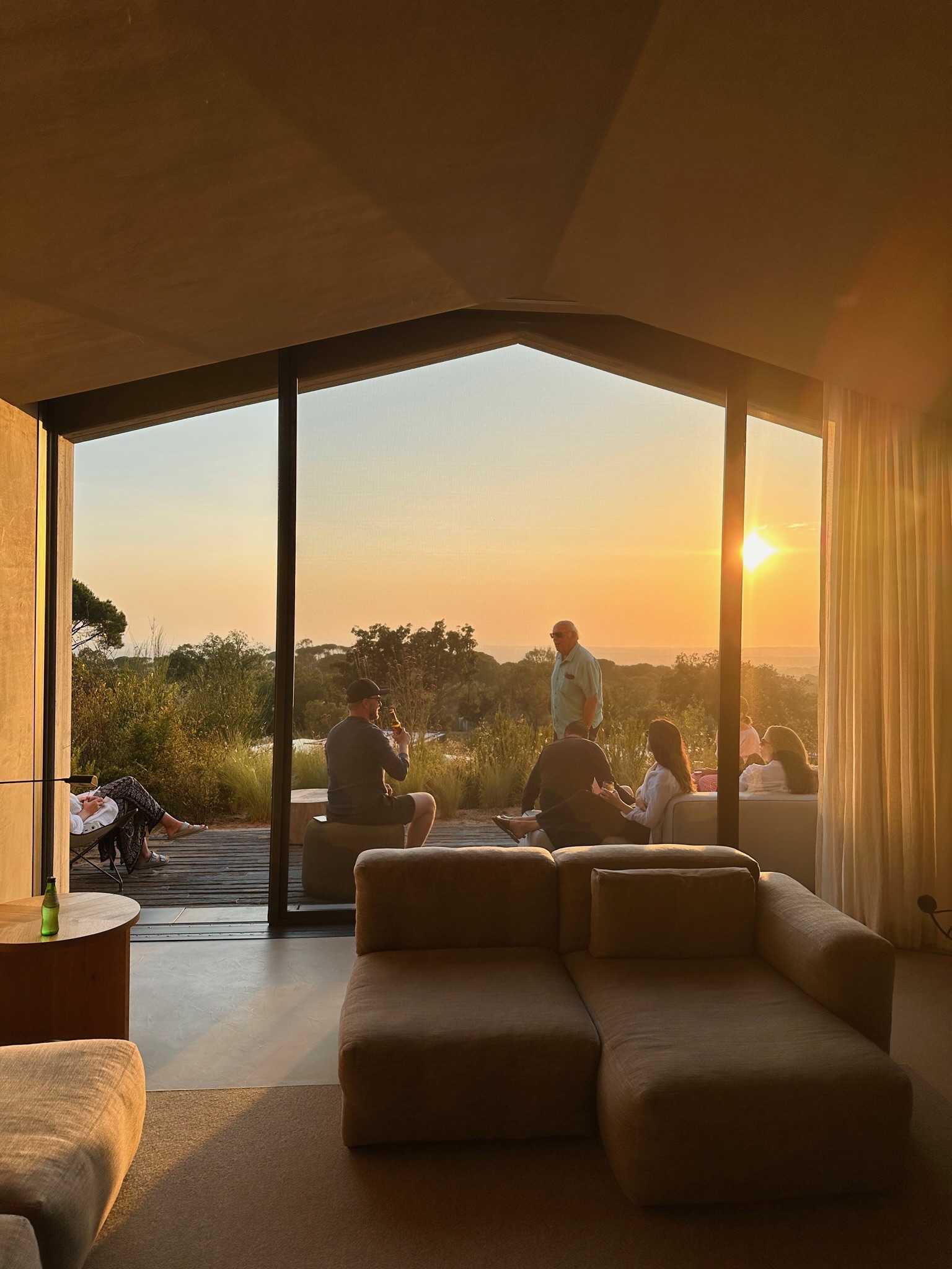 View of a group of people sitting and enjoying sunset seen through a large glass window