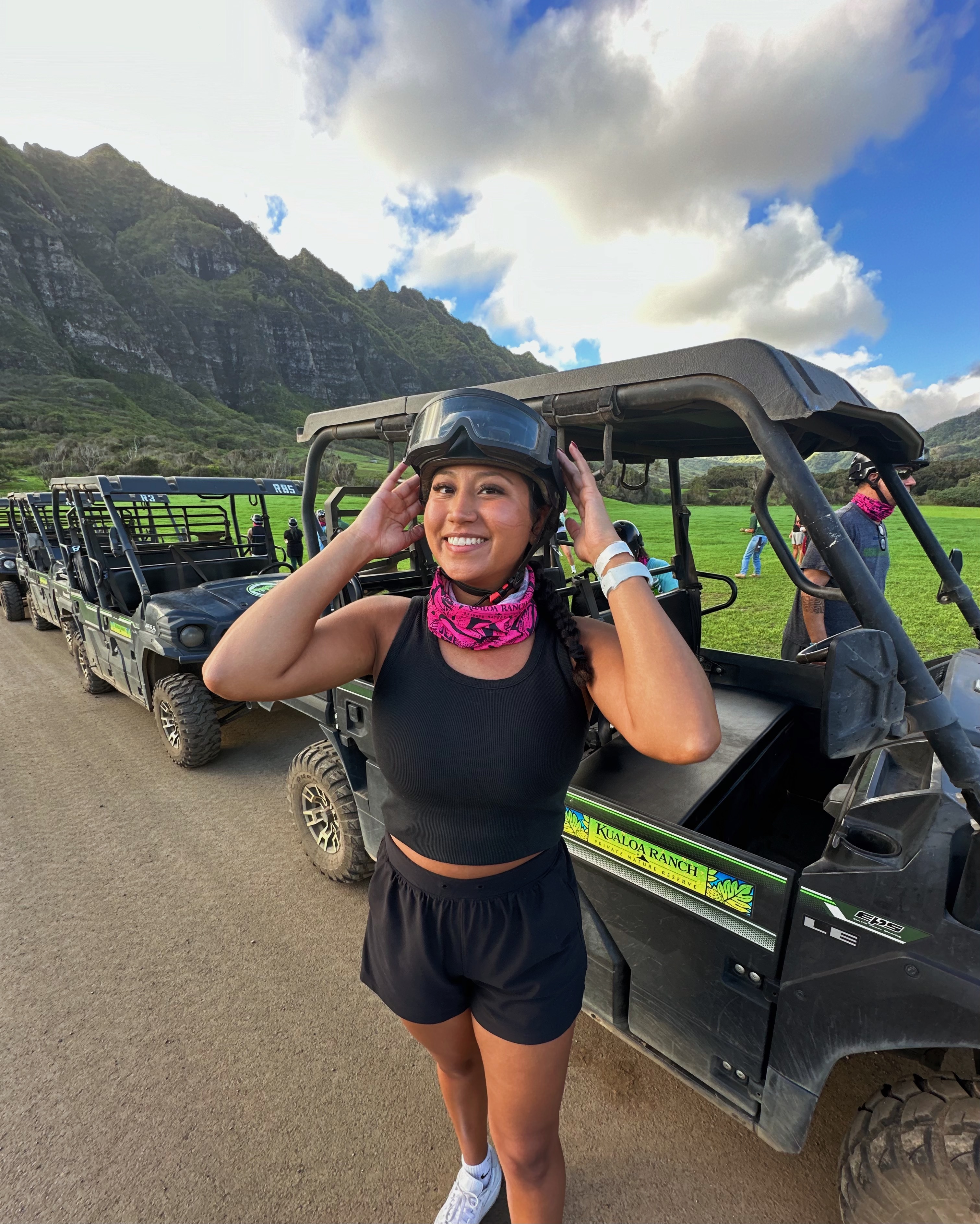 Advisor in a black helmet standing beside four-wheel vehicles in the mountains on a sunny day