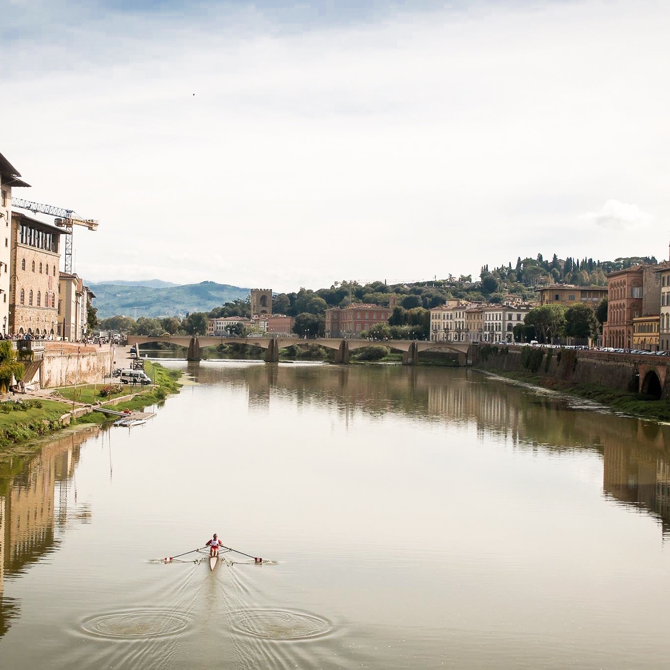 View of someone kayaking along the river on a cloudy day in Florence, Italy