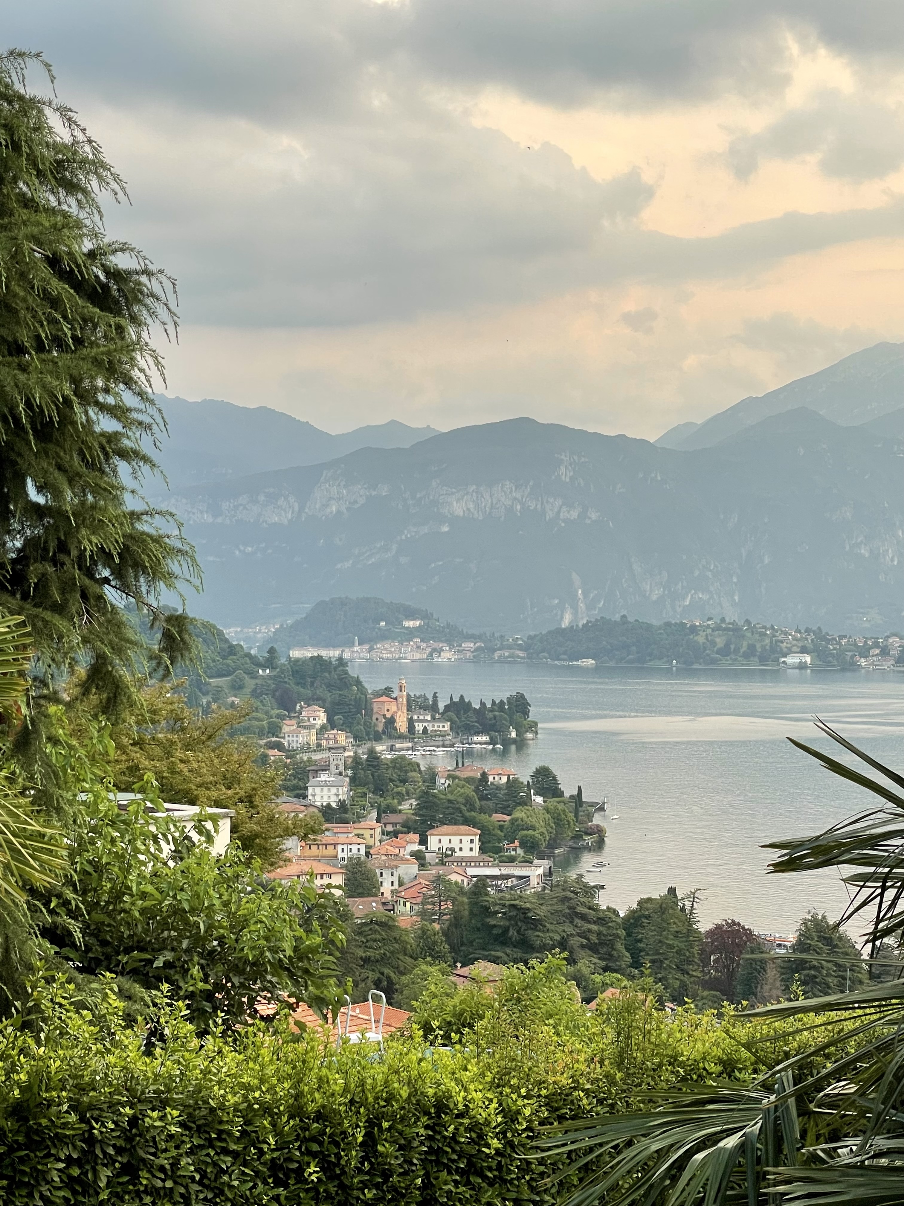 A view of a coastal town with mountains and lush foliage surrounding it next to a body of water.