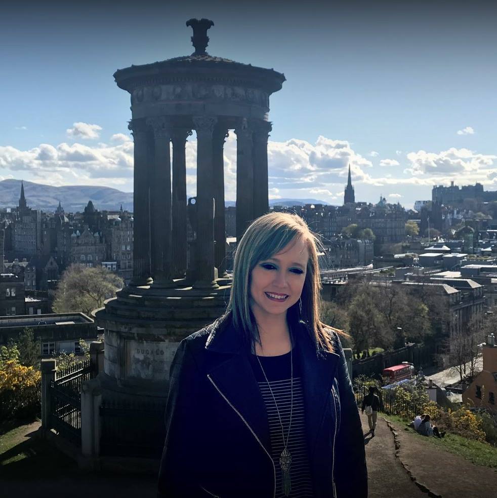 Advisor smiling at a viewpoint overlooking an old city with a church tower in the foreground on a sunny day