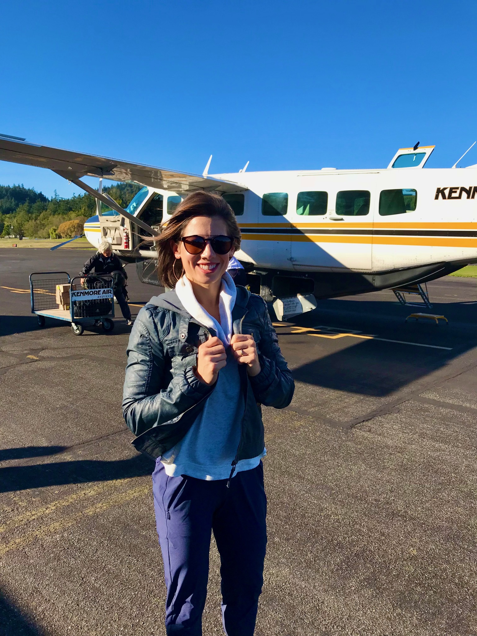 Advisor in sunglasses standing on the tarmac beside a small plane under clear skies