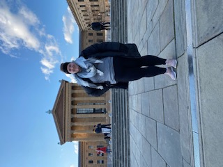 Debbie posing in front of a monumental building during the daytime.
