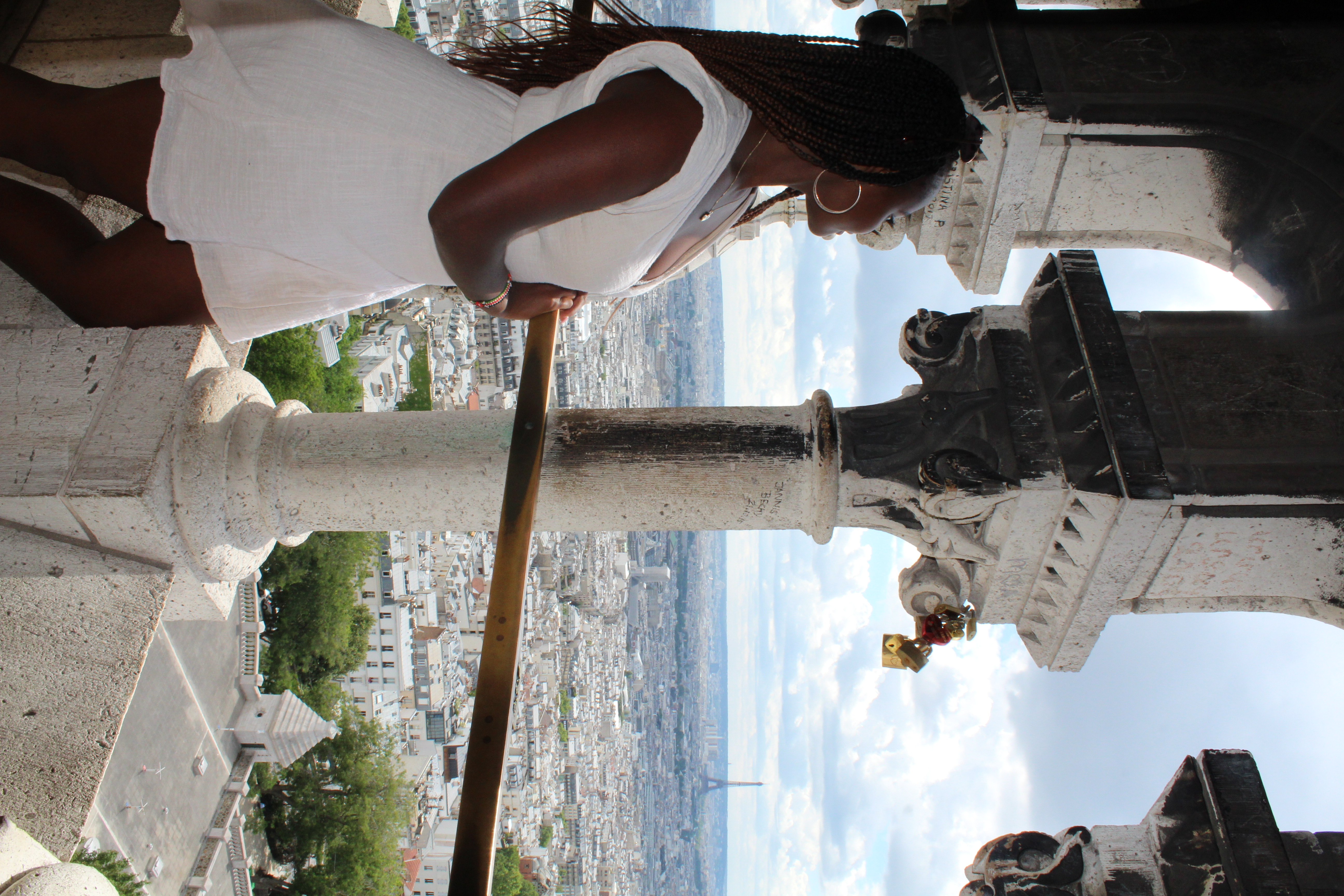 Advisor in a white dress on a balcony looking out over the Paris skyline on a cloudy day