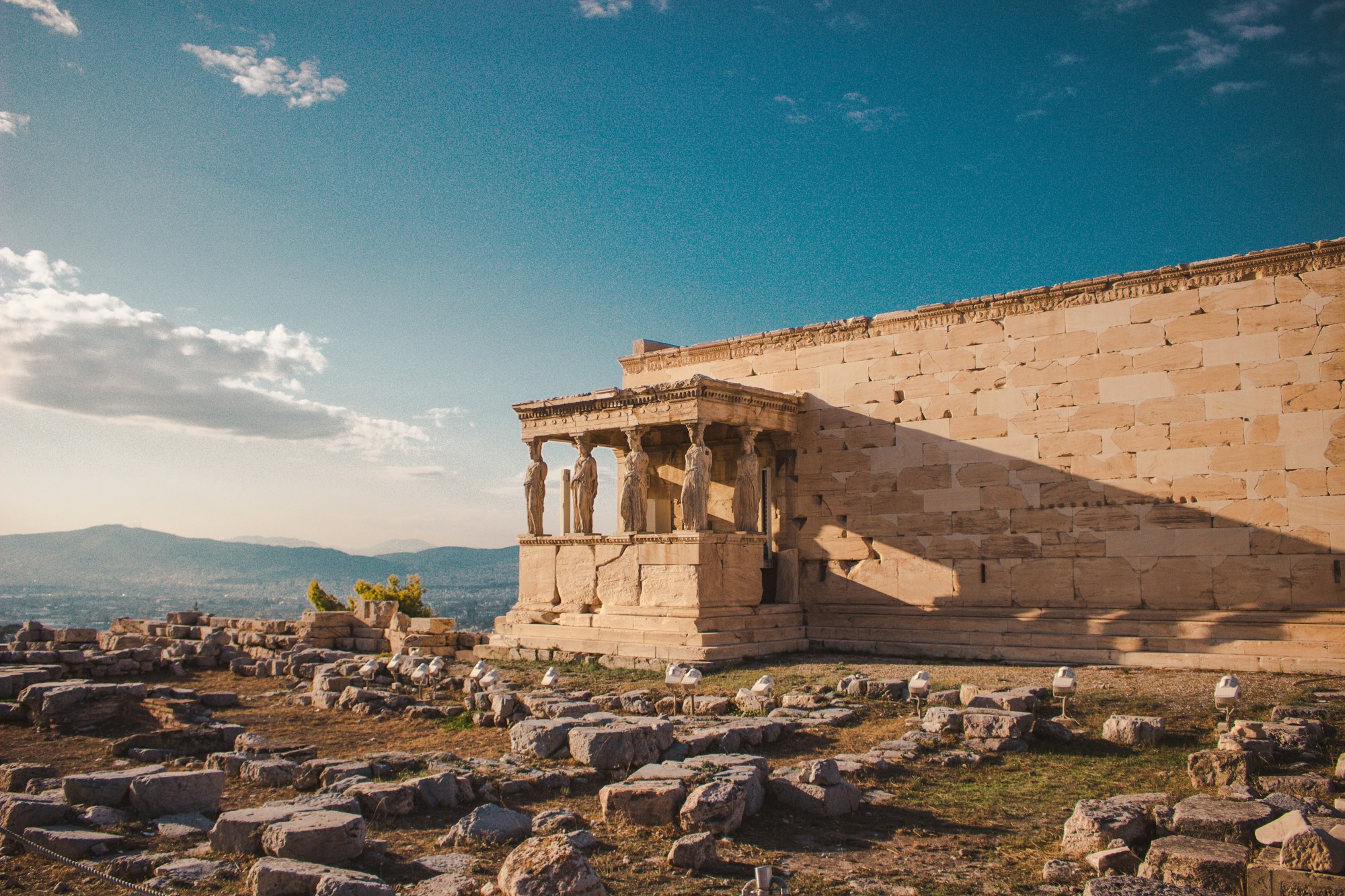 Ancient ruins bake under a setting sun as clouds float past.