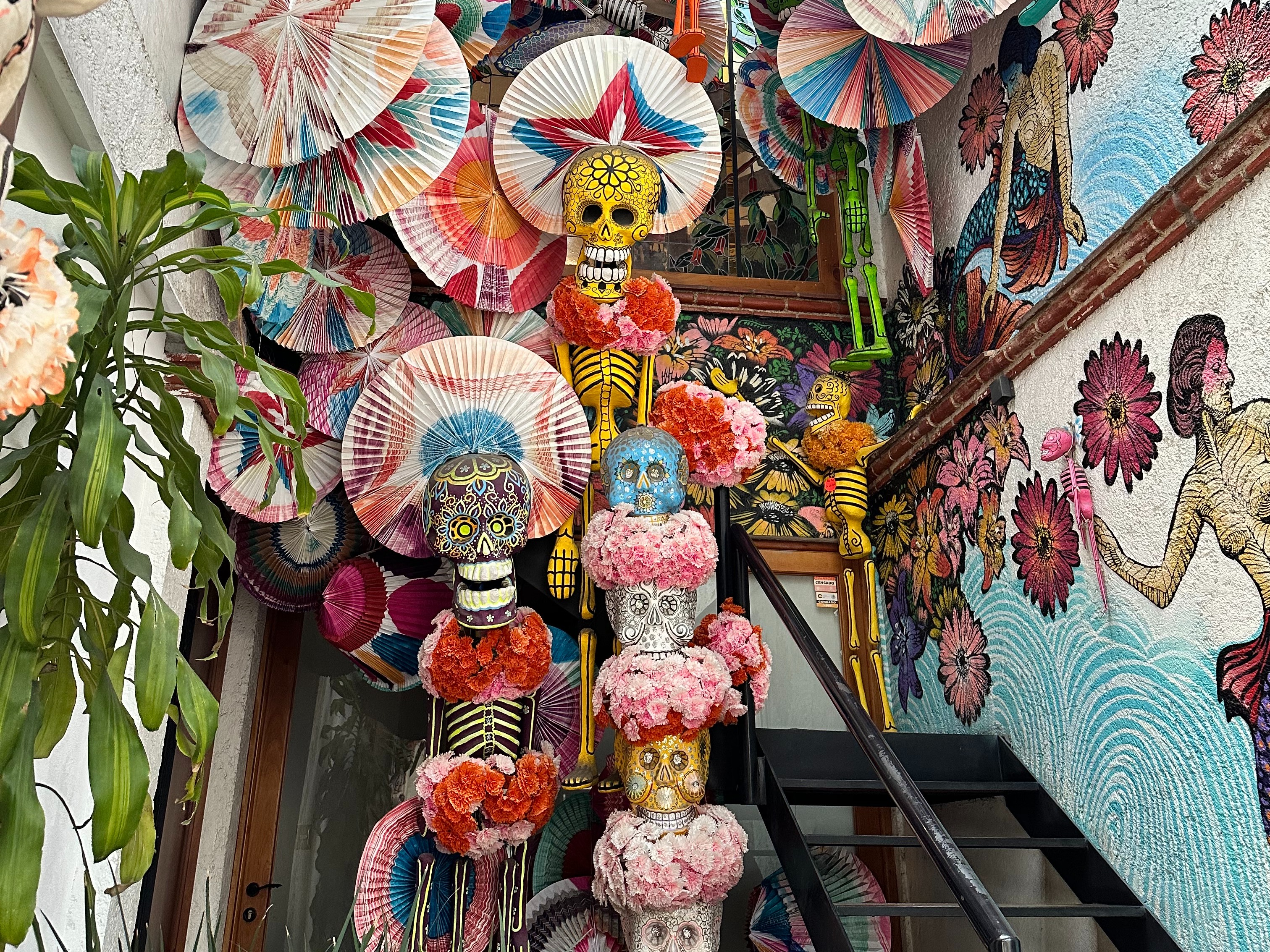 A vibrant collection of colorful traditional paper fans, flowers and skulls