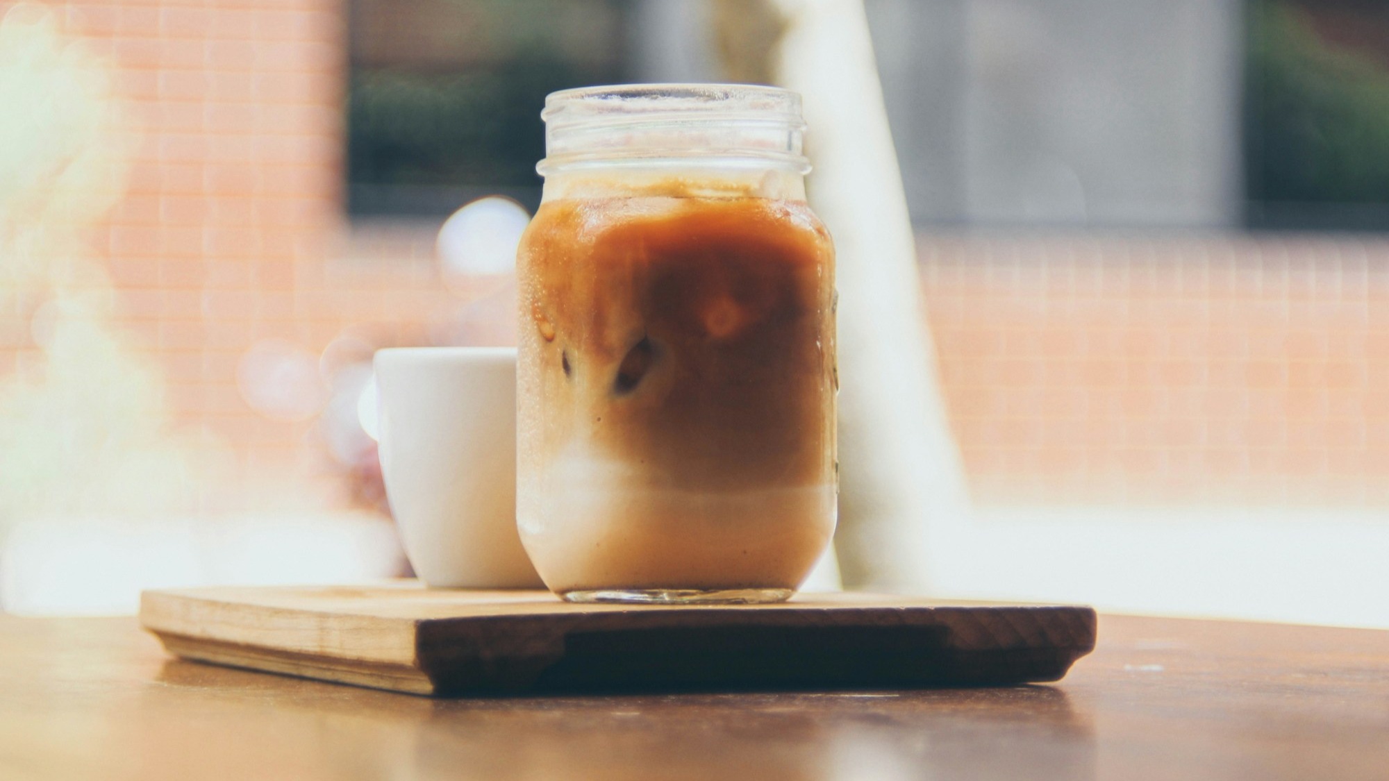 A mason jar of iced coffee with cream.
