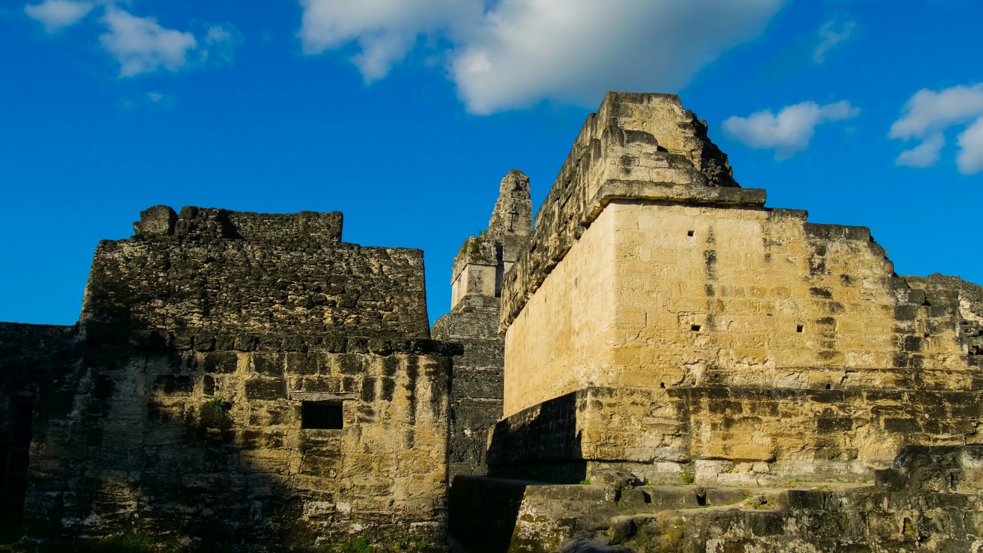 Ancient ruins with a blue sky filled with wispy clouds overhead.