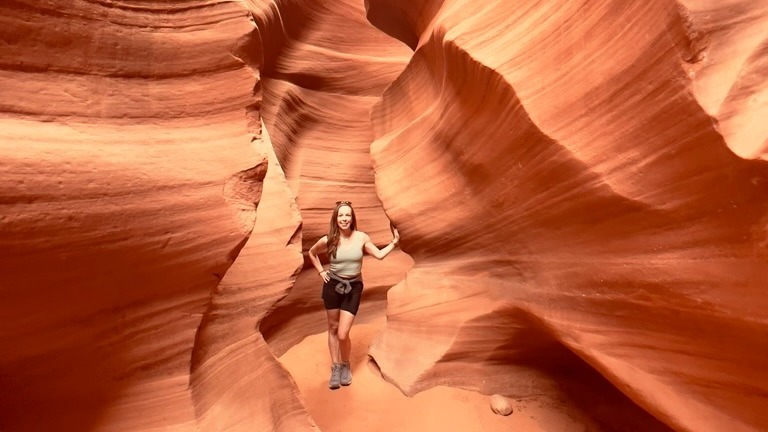 Advisor standing within the striated red rock of a slot canyon.